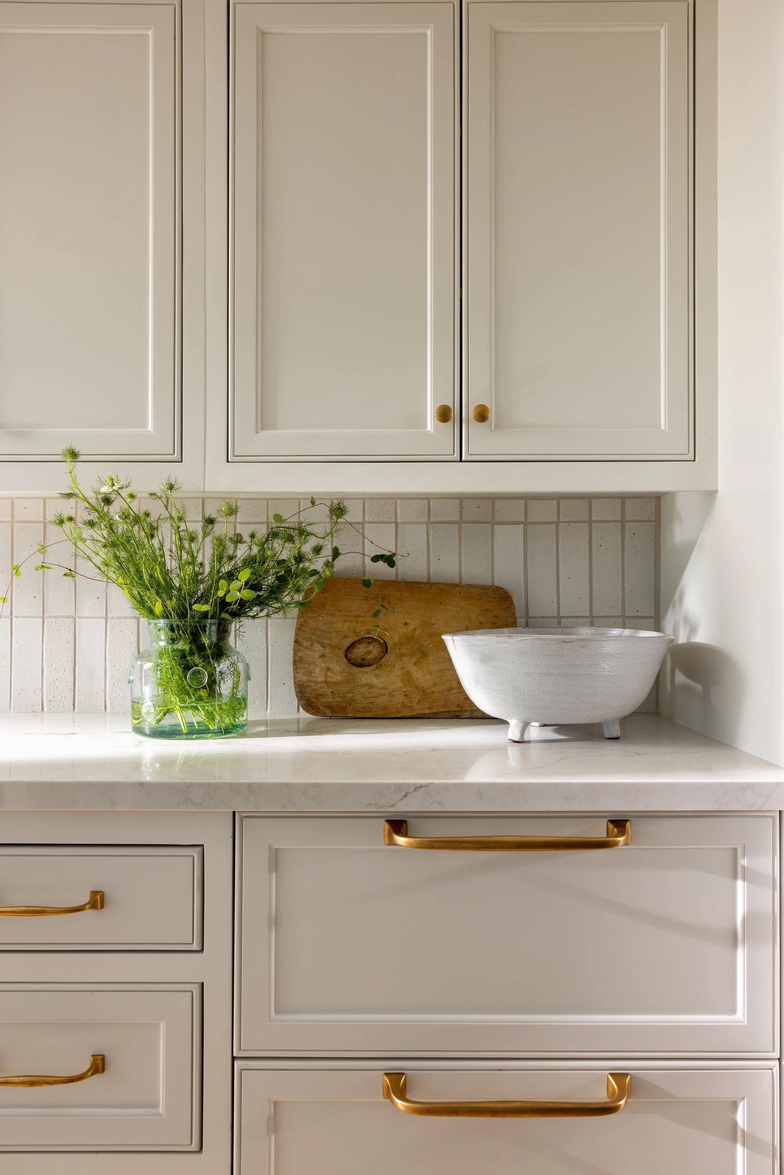 Kitchen counter detail with marble surface, brass drawer pull, subway tile backsplash, and ceramic bowl — Bartlett Residence by Tama Bell Design, Ukiah CA