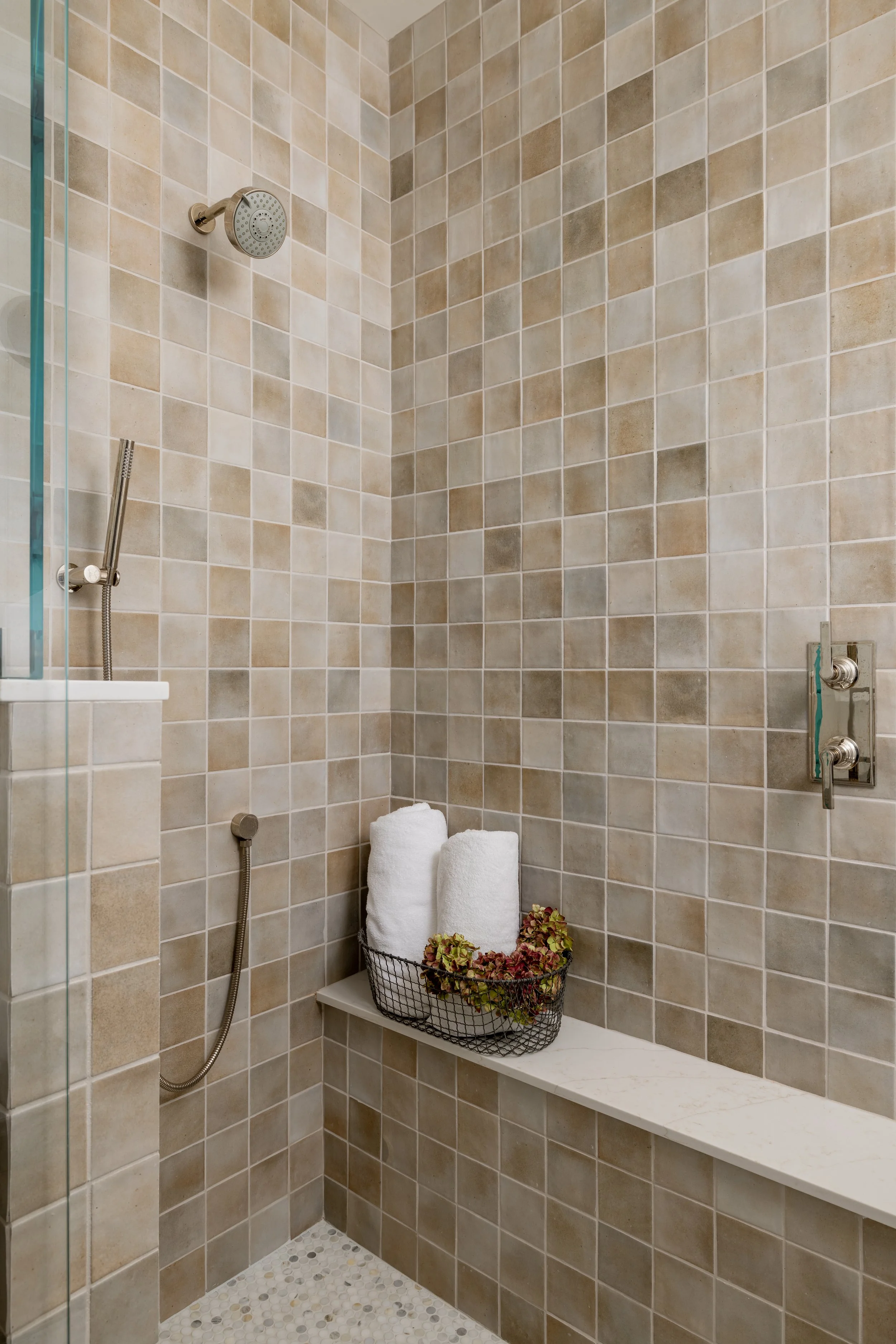 Walk-in shower with warm square tile, built-in bench, pebble floor, and glass enclosure — Bartlett Residence by Tama Bell Design, Ukiah CA