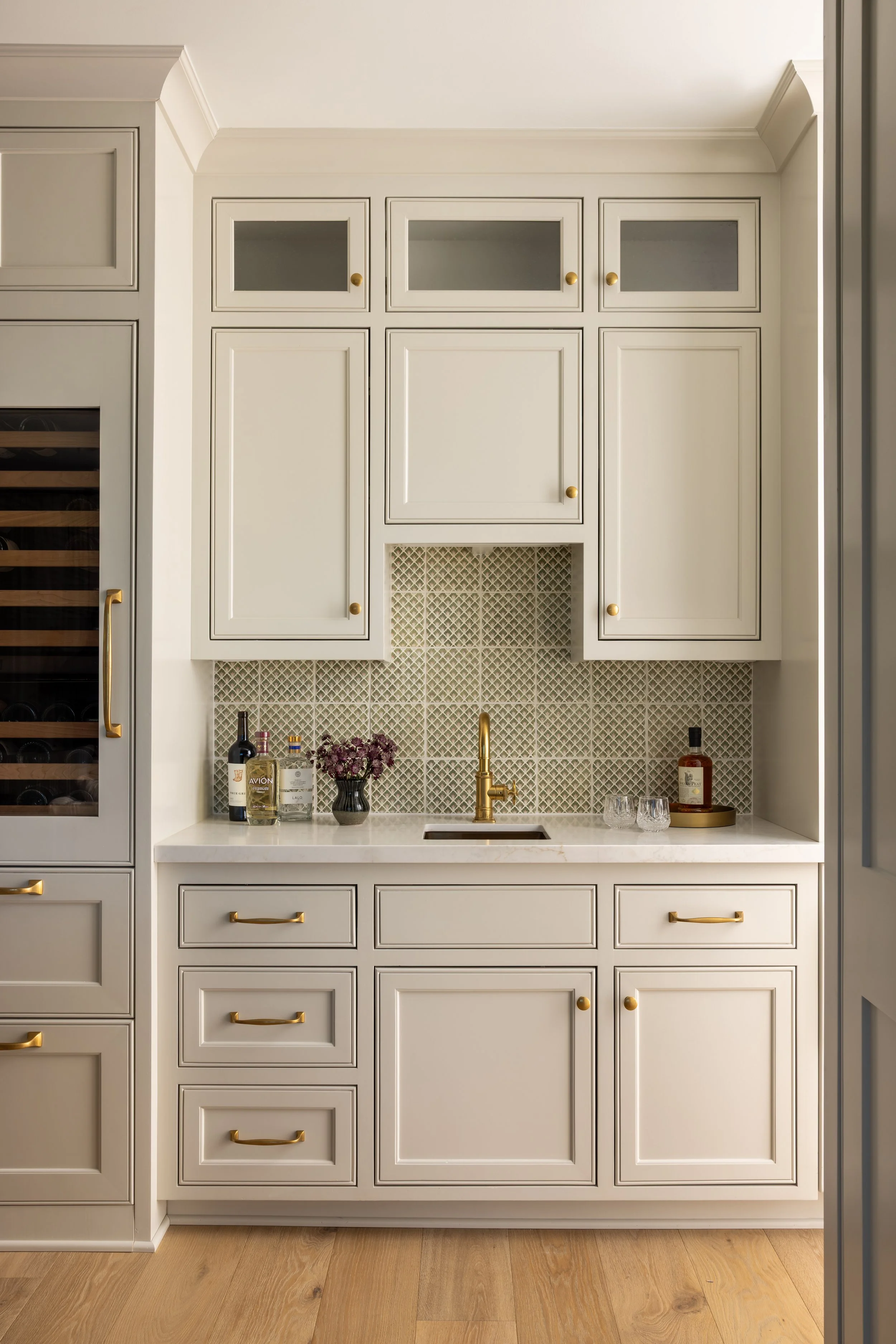 Built-in wet bar with patterned tile backsplash, brass faucet, wine fridge, and cream cabinetry — Bartlett Residence by Tama Bell Design, Ukiah CA