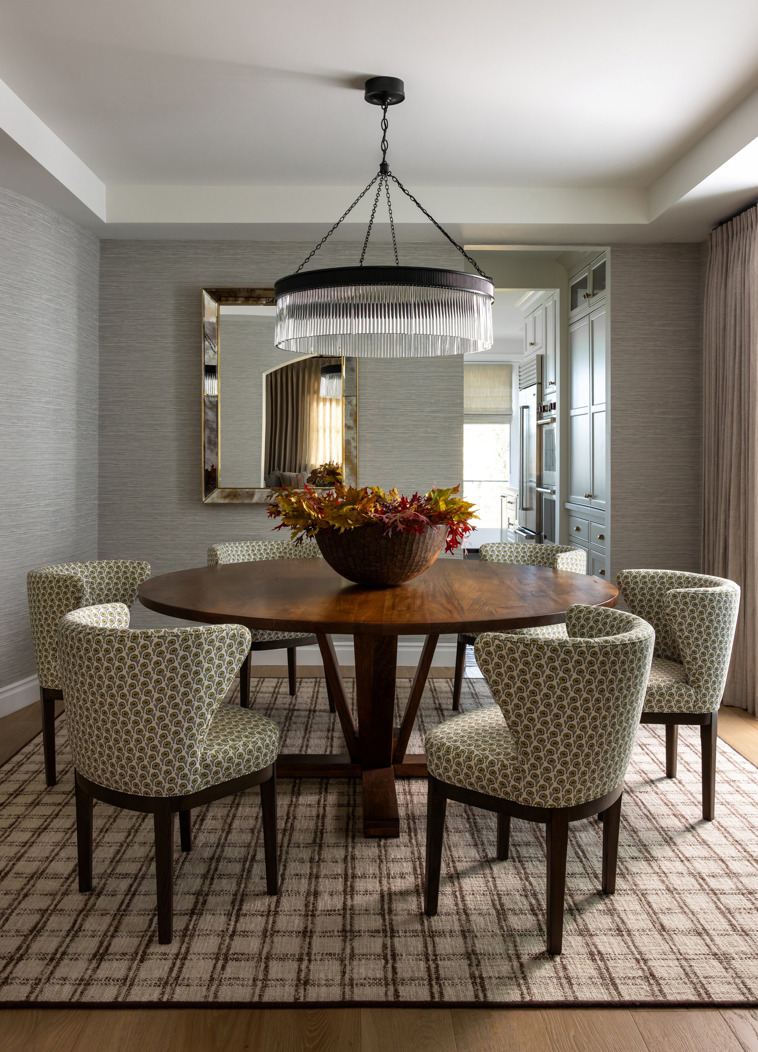 Transitional dining room with round walnut table, patterned upholstered chairs, and tiered glass chandelier — Bartlett Residence by Tama Bell Design, Ukiah CA