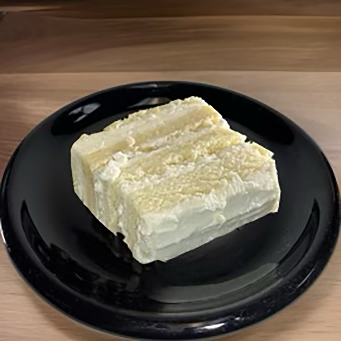 Slices of layered vanilla or lemon cake with cream filling on a black plate