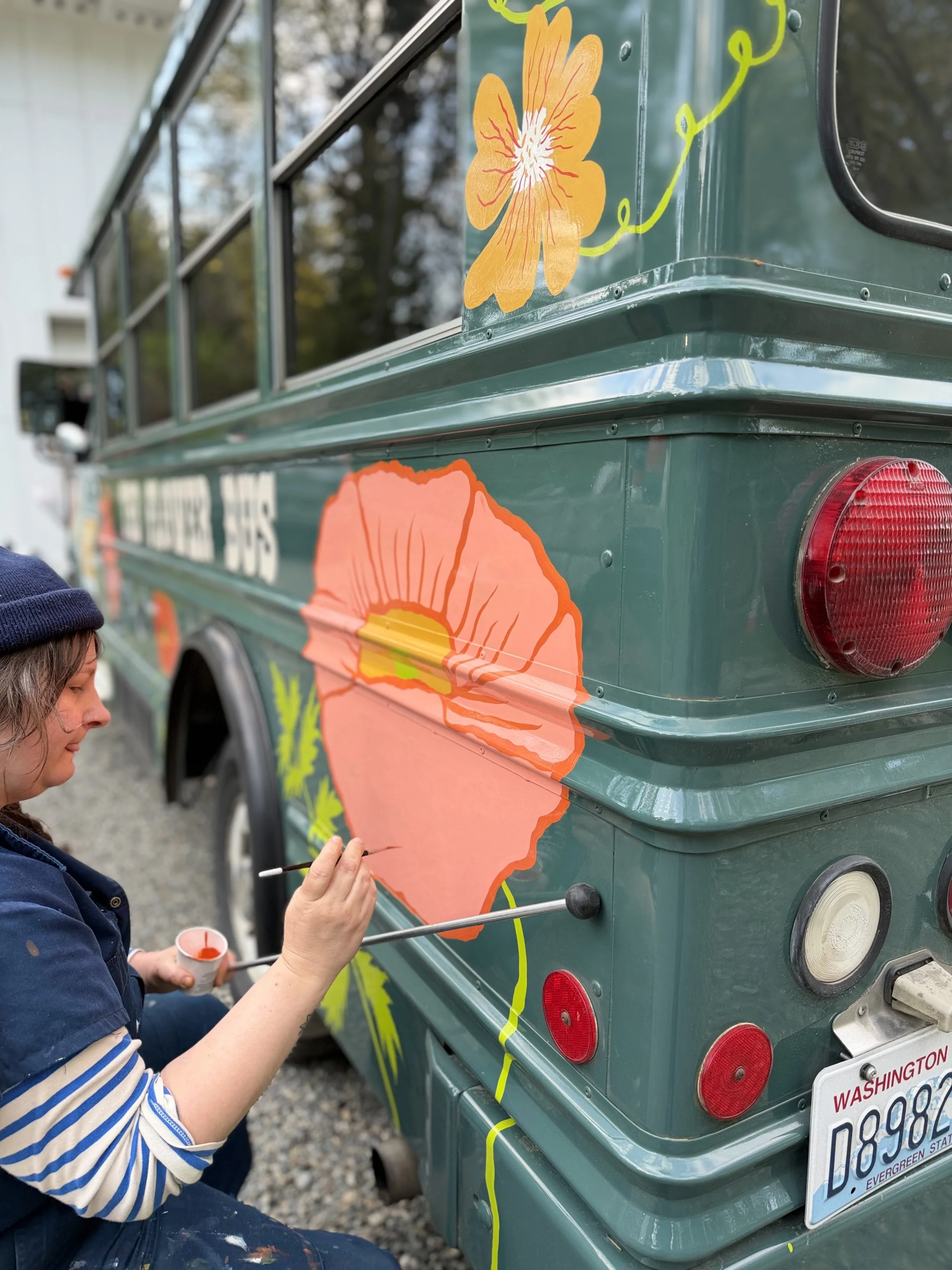Molly Wheat Baker painting the Icelandic Poppy on the back end of the bus