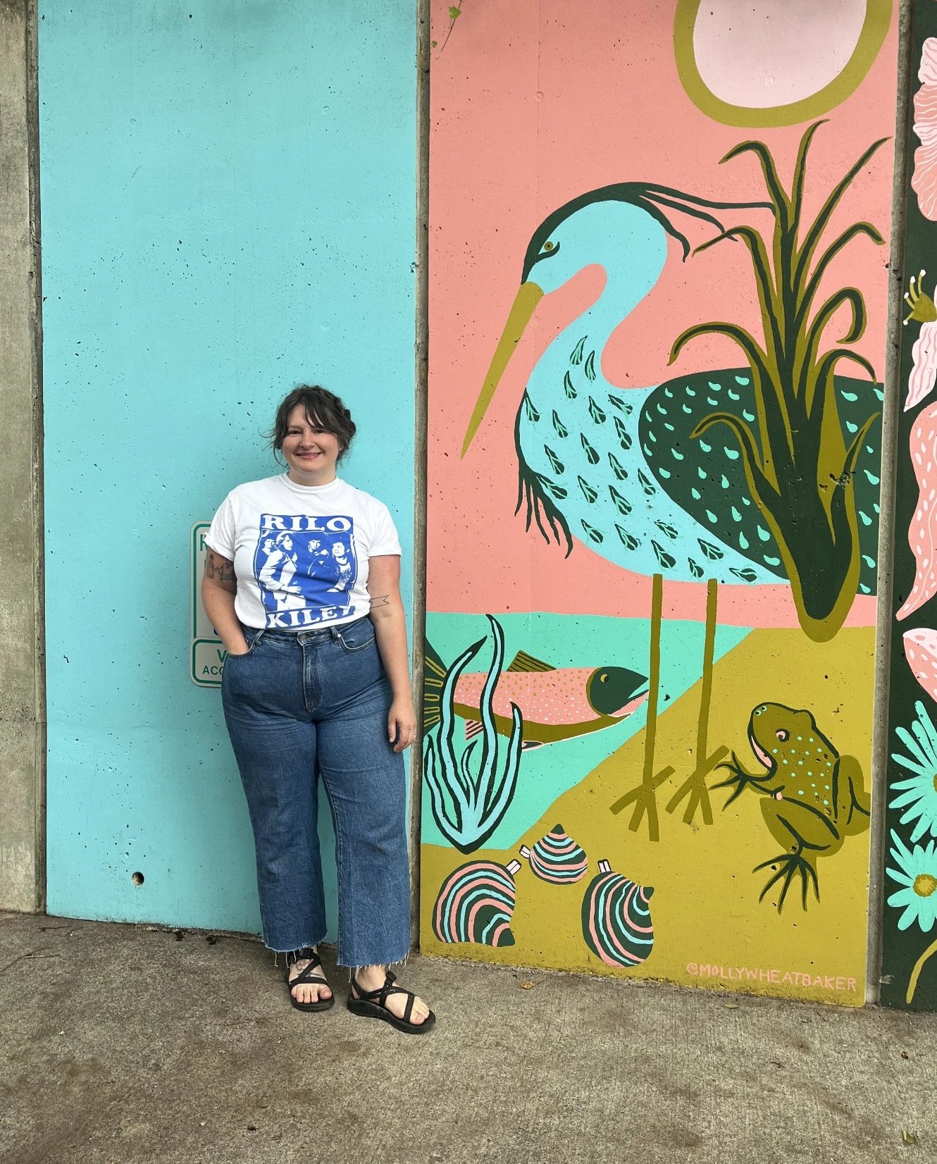 Molly Wheat Baker standing with her beautiful mural