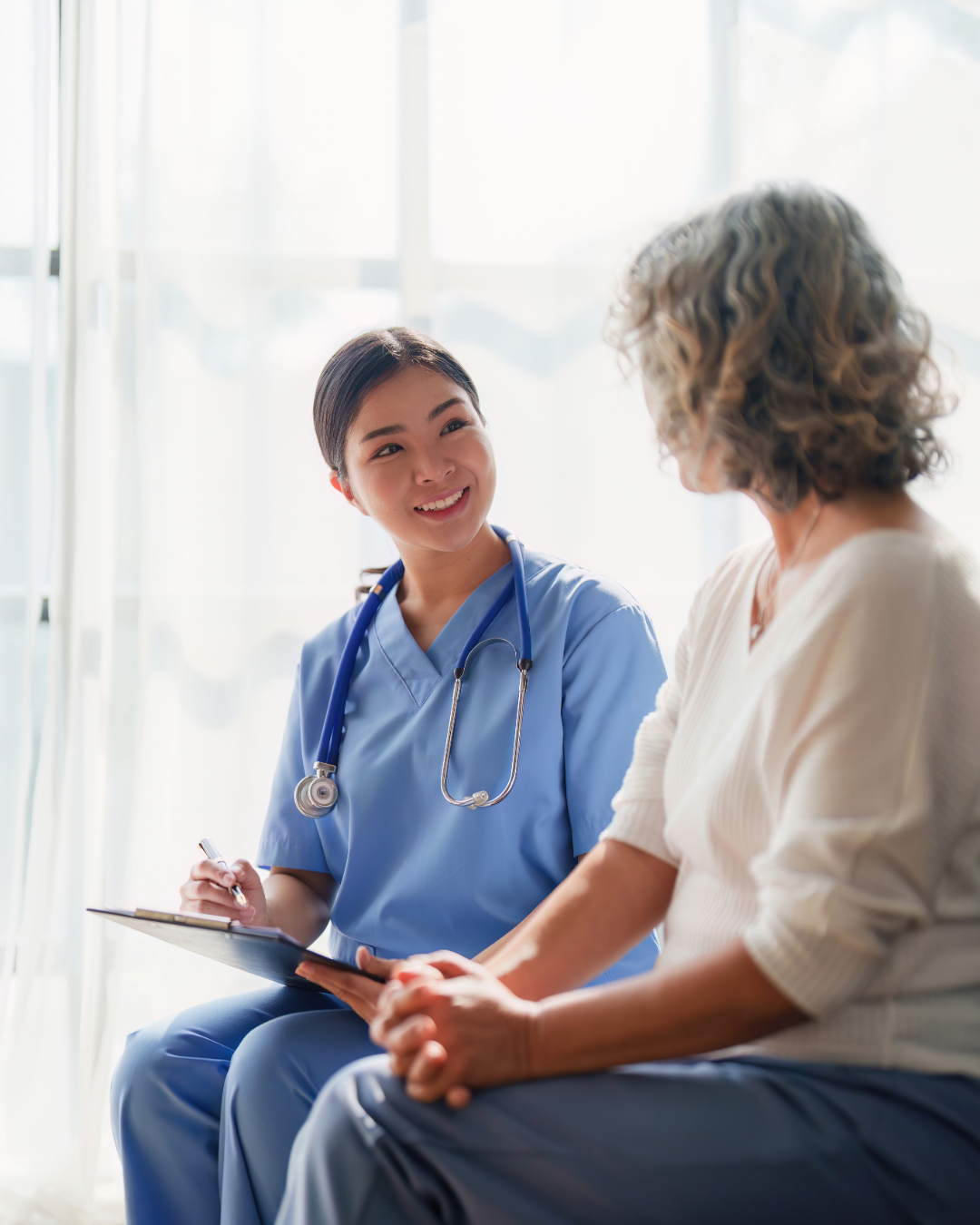 Licensed nurse in blue scrubs speaking with a senior patient in a healthcare facility in Washington State