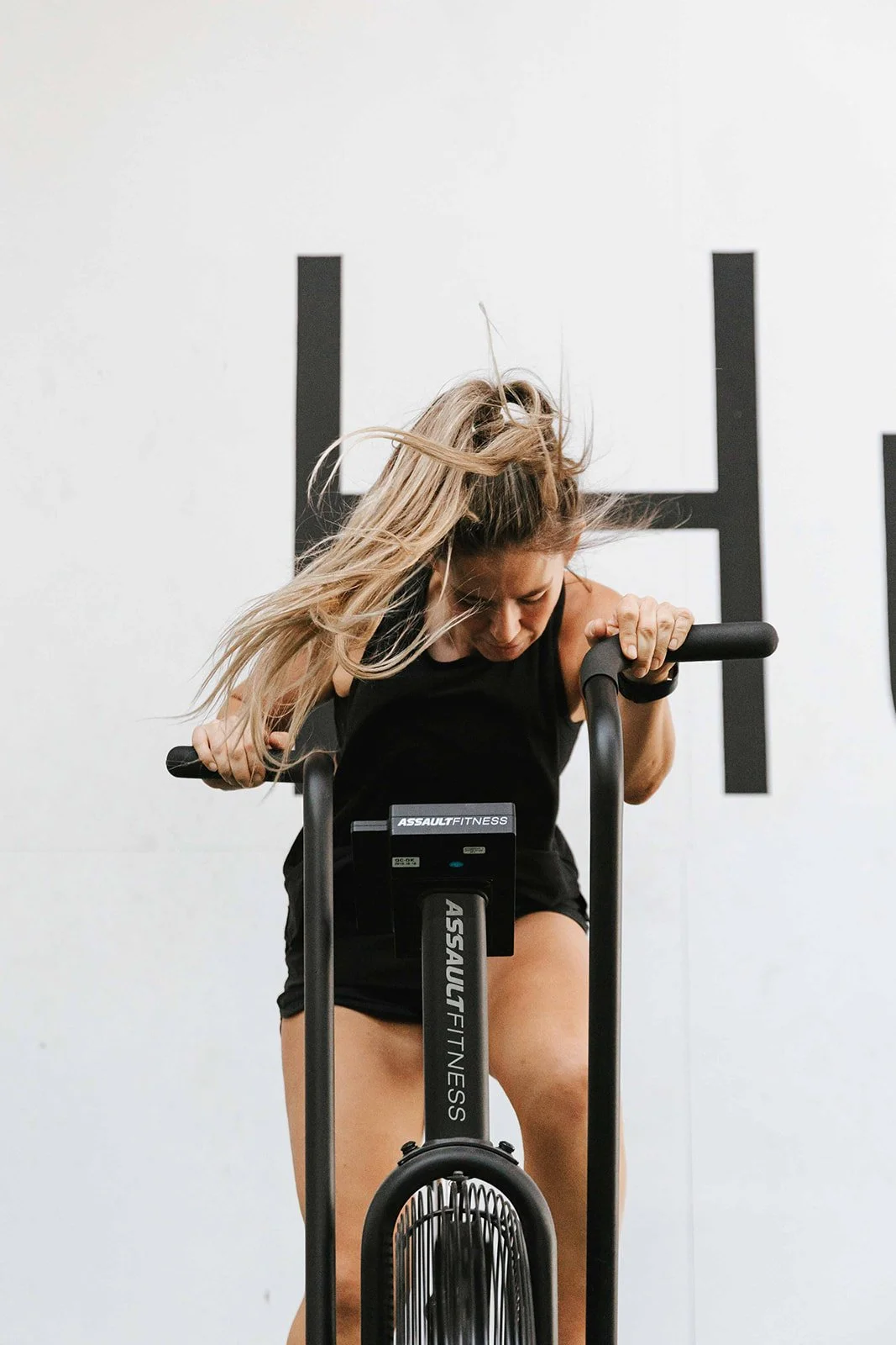 Lady working out on an assualt bike.
