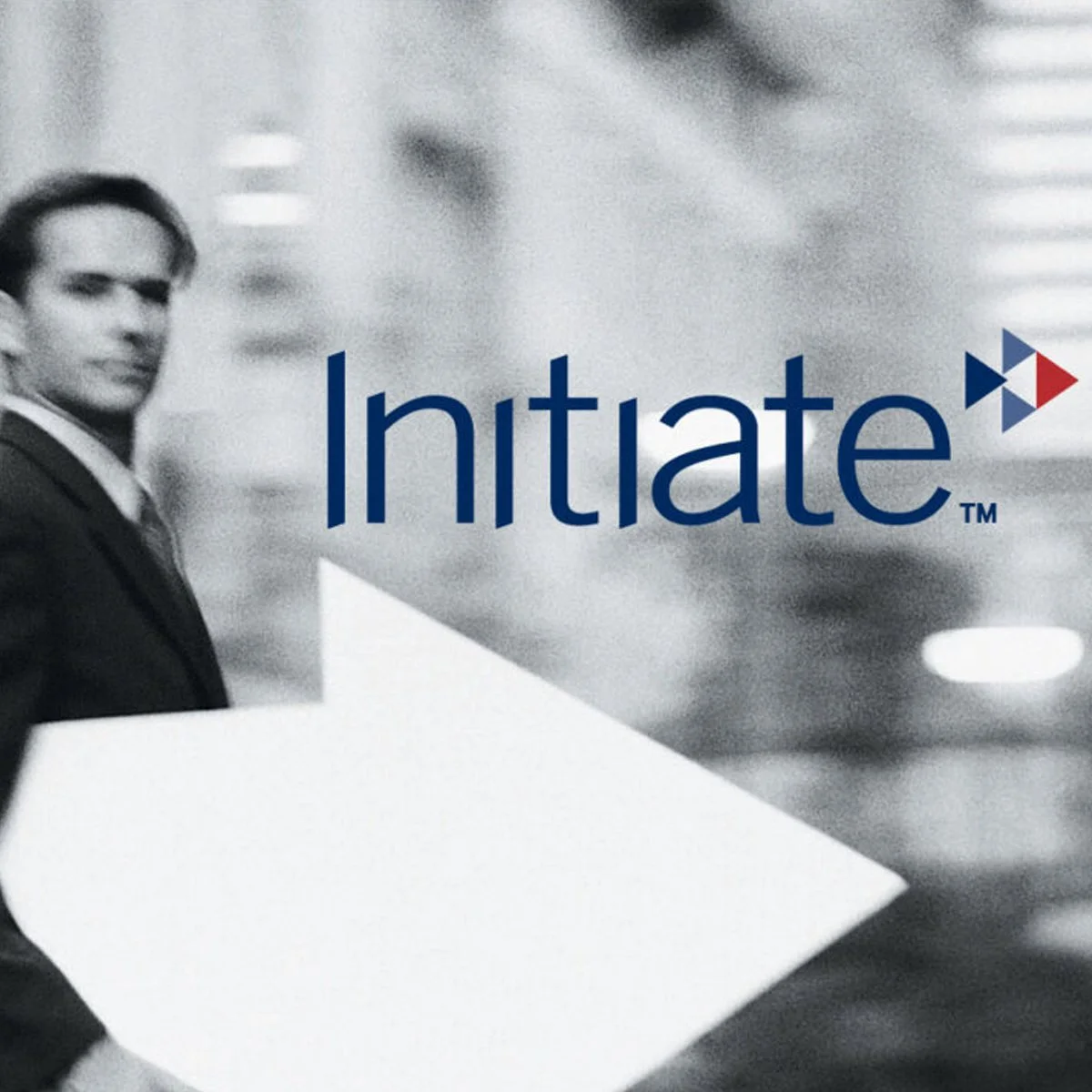 A black and white photo of a man in a suit holding a document with the word "Initiate" written across it. The background shows blurred office buildings.