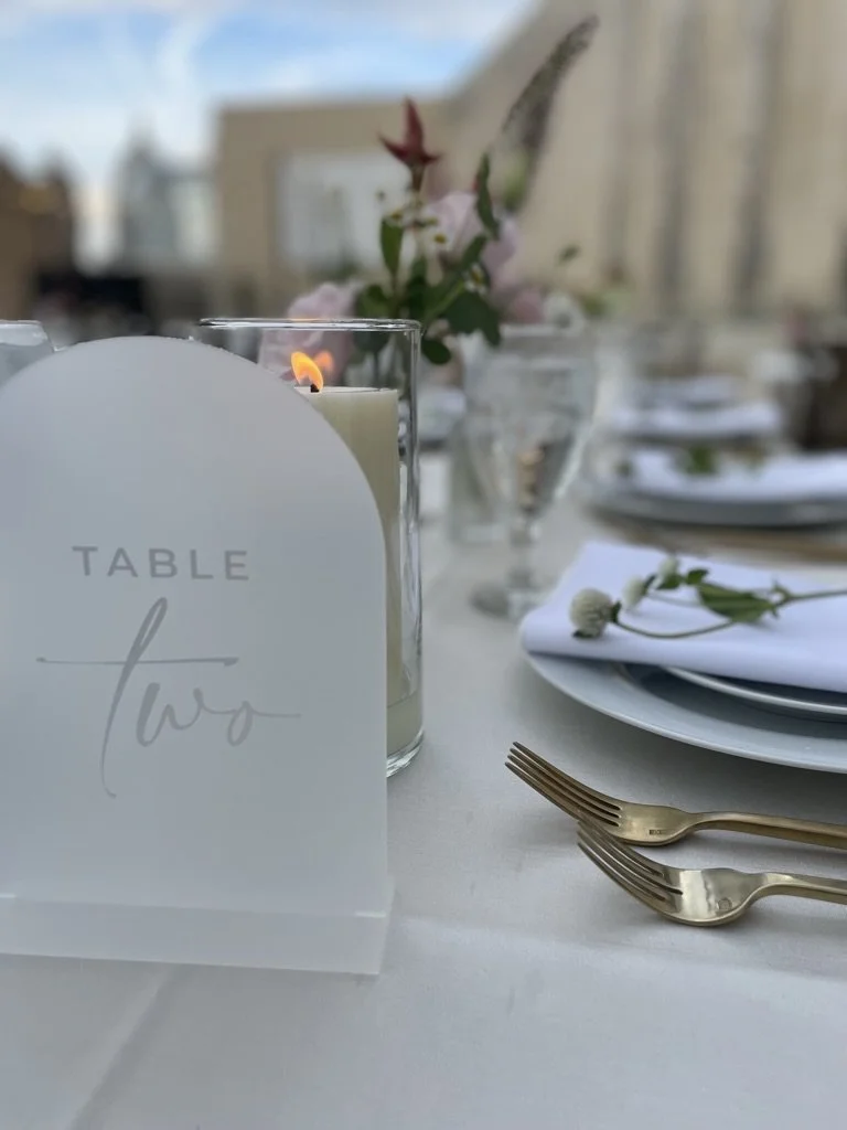 A candlelit table set with flowers and gold flatware