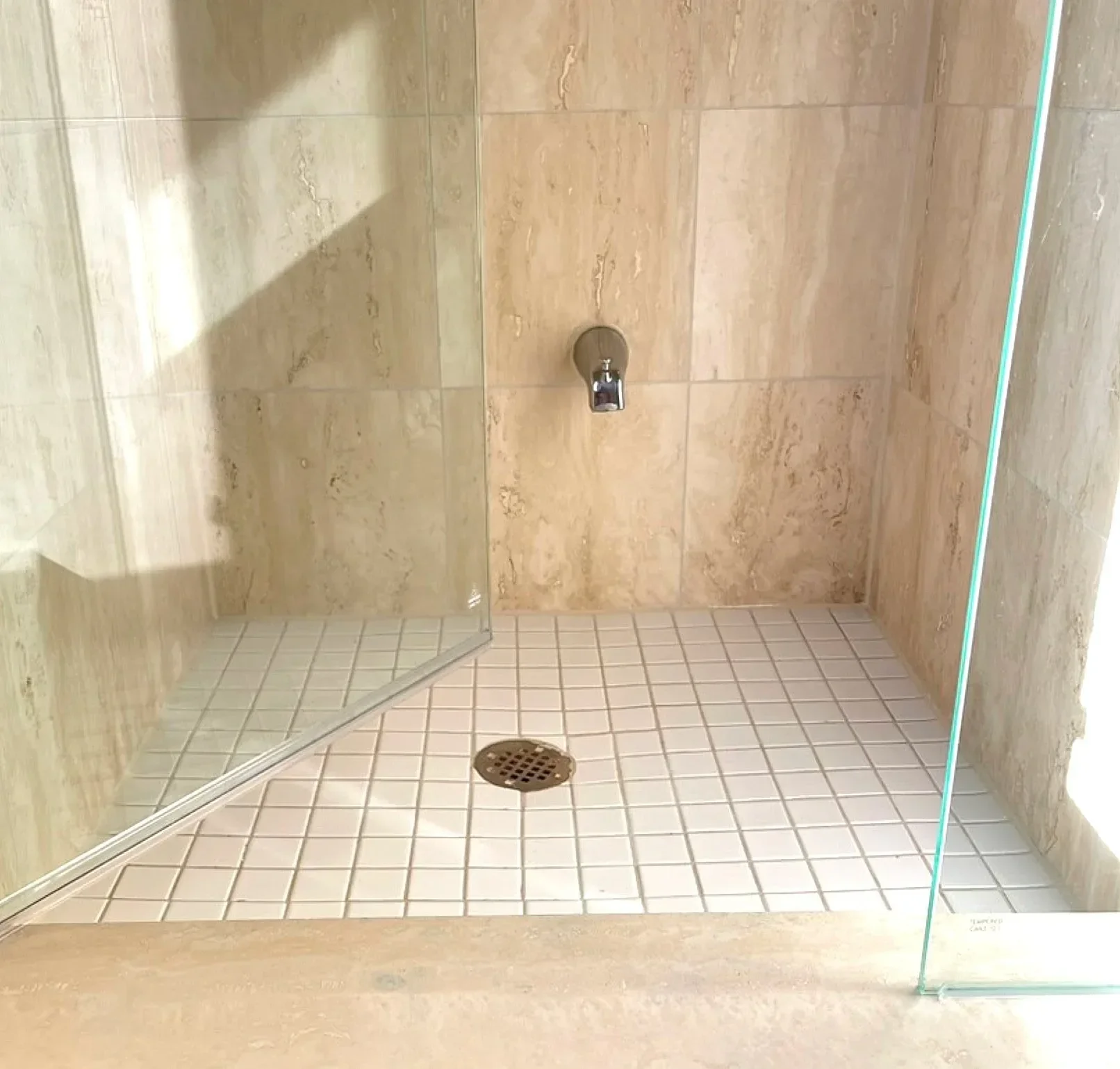 Walk-in shower with newly restored tile and grout for wall and floor with open glass door