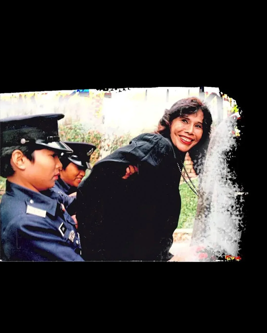 Mona smiling as she’s being placed in a police van