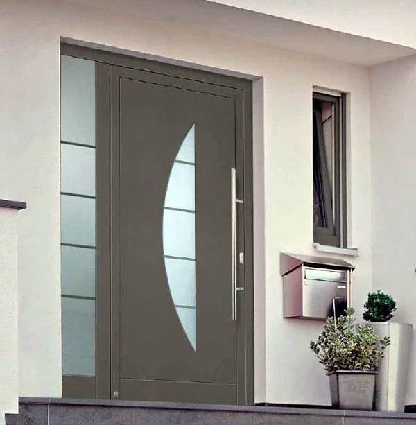 Porte d'entrée grise avec un motif de lune en lumière, près d'une fenêtre et un panneau à courrier, avec des plantes en pot à côté.