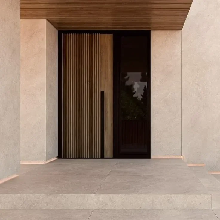 Une porte d'entrée moderne en bois avec des volets en bois vertical, encadrée par des murs en pierre clair, sous un plafond en bois.