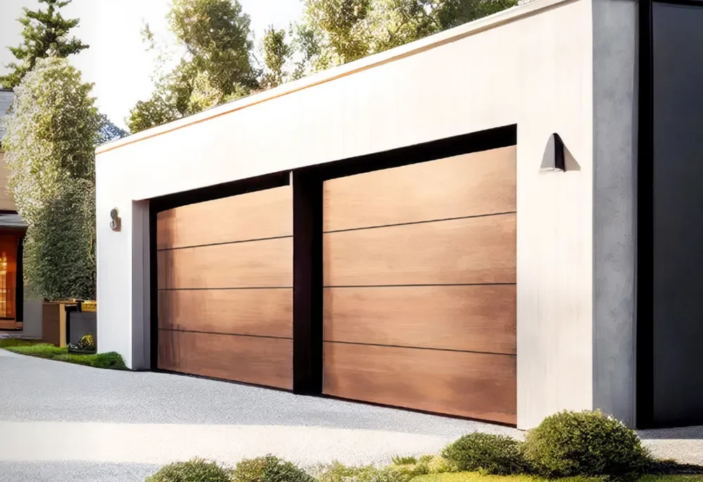 Garage moderne avec portes en bois et façade en béton blanc, entouré d'un jardin avec des buissons et des arbres.