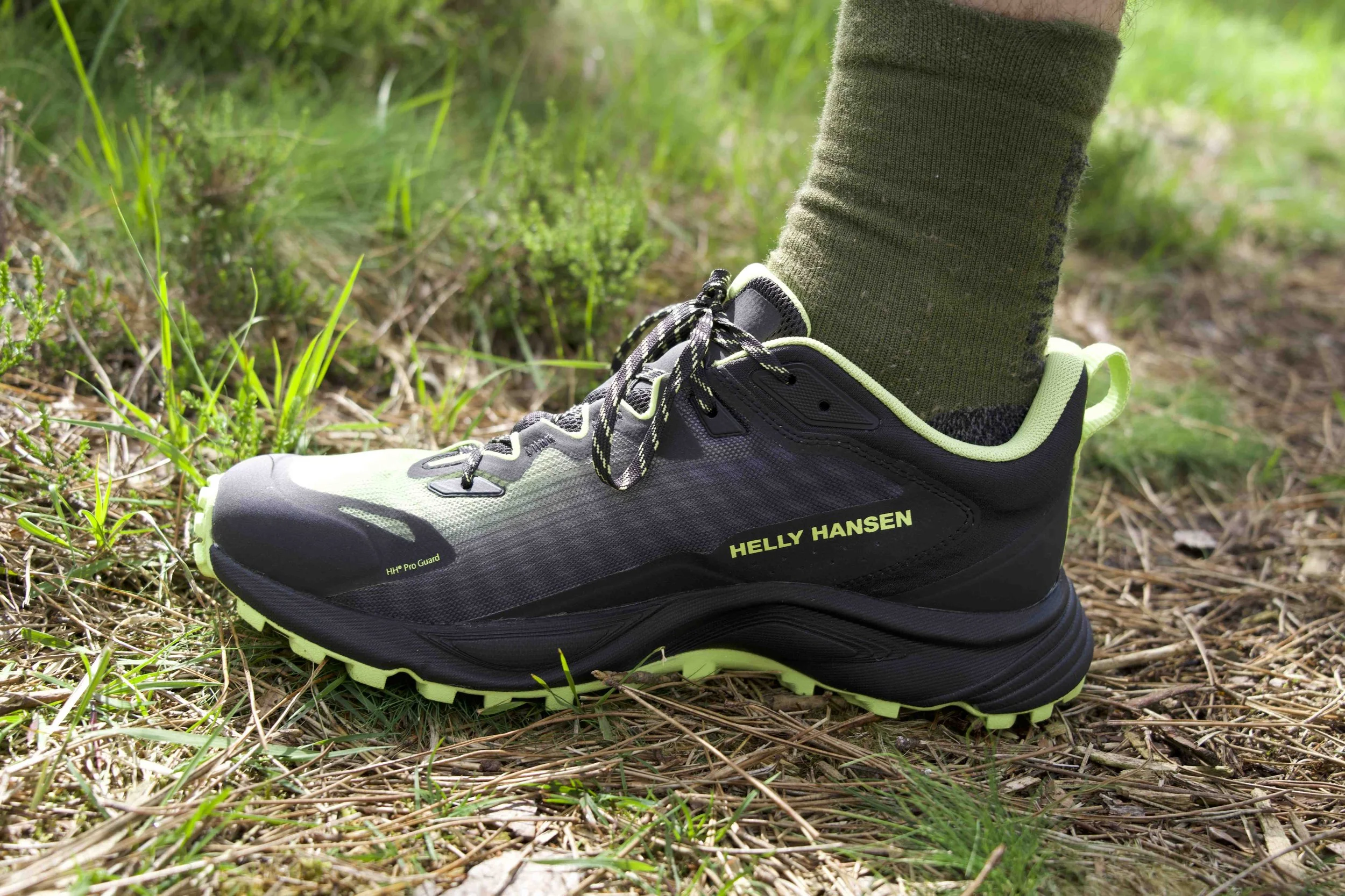 Close-up of a hiking shoe on a forest trail with grass and dirt