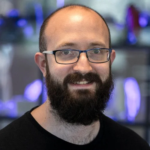 A bald, bearded man with glasses, looking knowingly into the camera. It's Me, I'm the man.