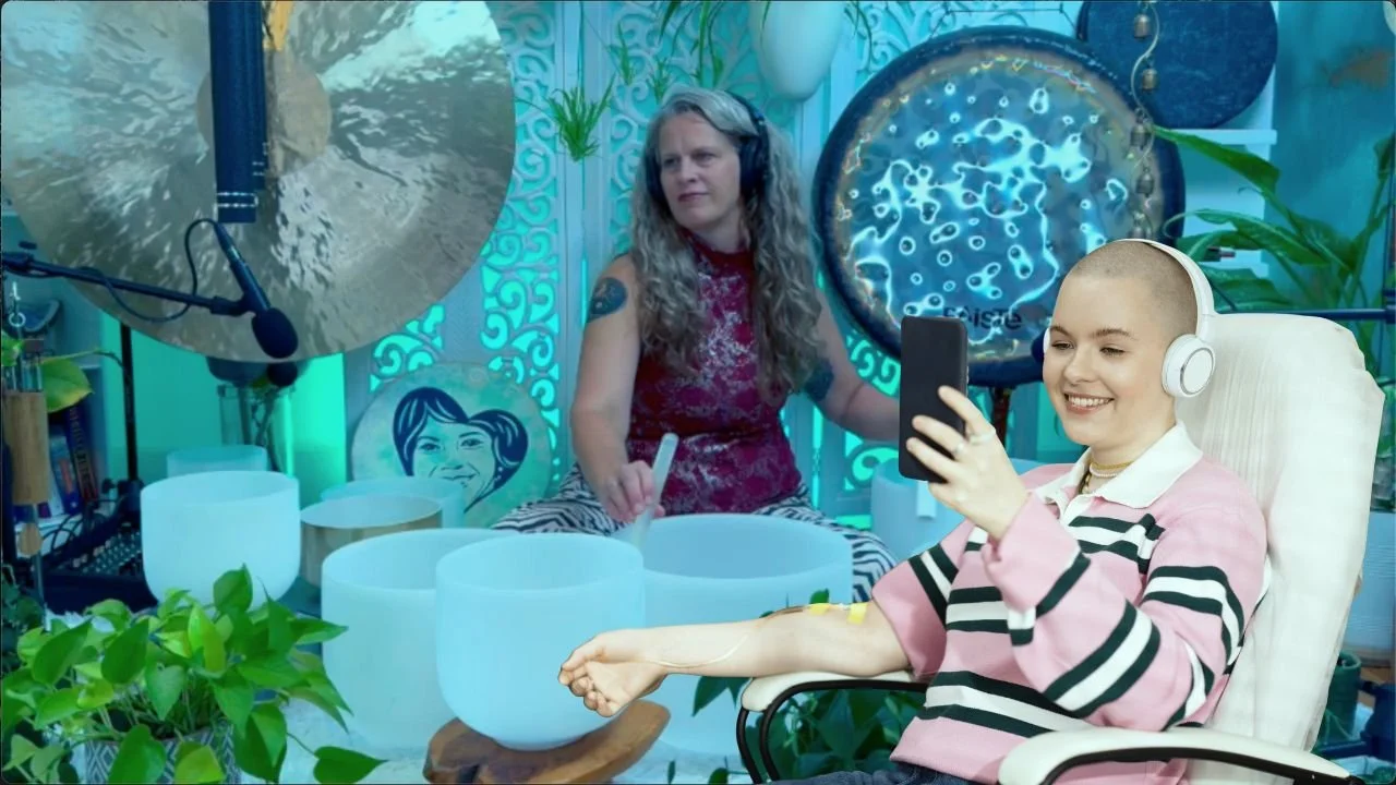 Photo of woman with headphones receiving chemo looking at phone