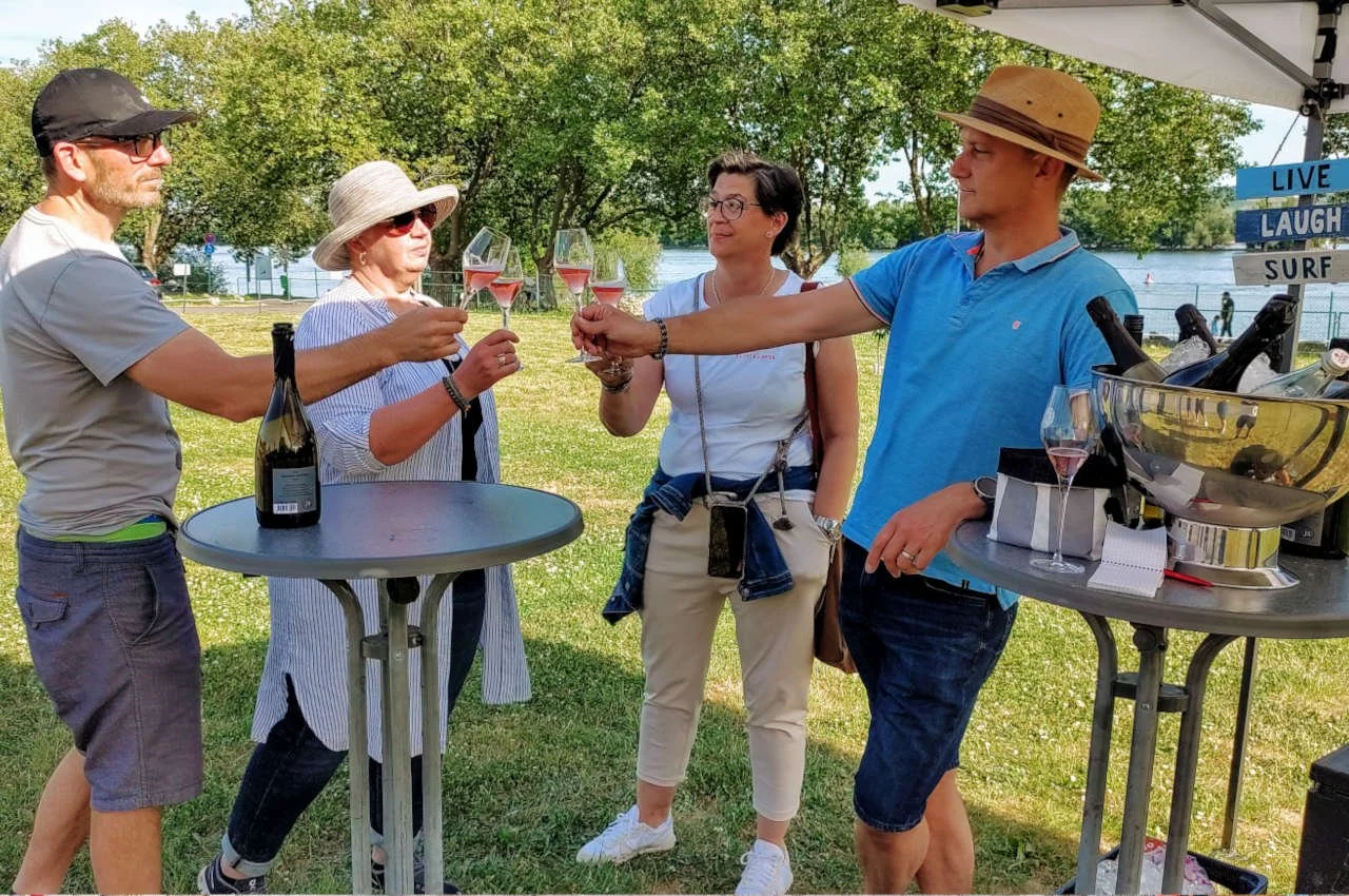 SChöner Sommertag. Zwei Pärchen stoßen mit Wein und Sekt an.