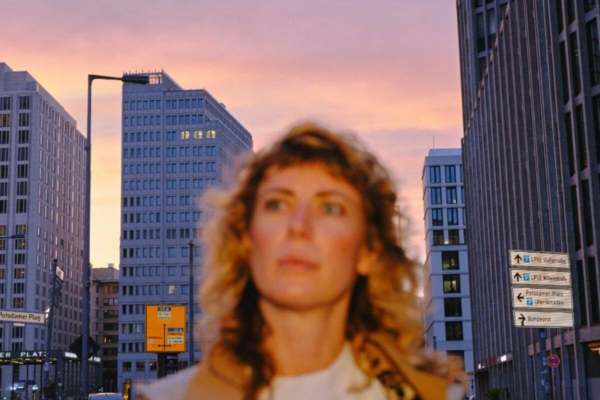 Woman standing among city skyscrapers at dusk, adjusting after landing in a new time zone