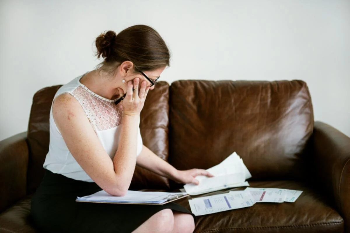A woman looking at medical papers while sitting in a couch