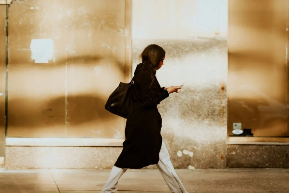 A woman walking while looking at her phone