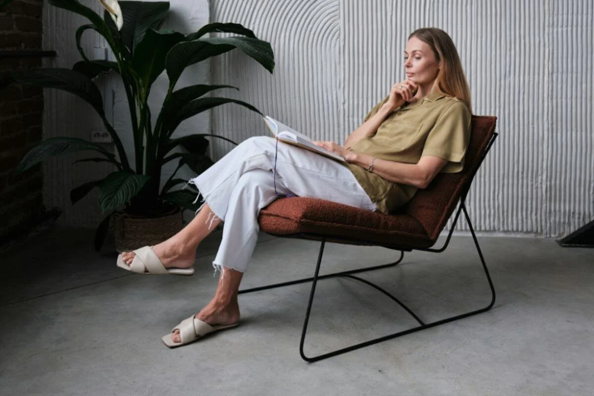 Woman reading a book while sitting down in a brown chair