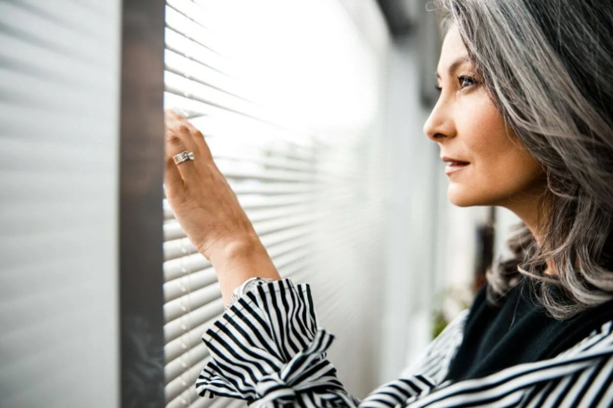 A woman in her 50s looking through a window