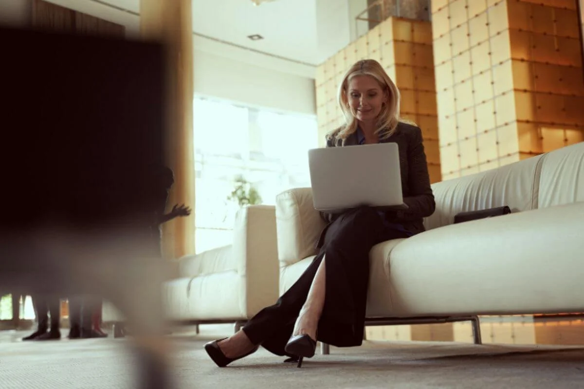 Founder working from a hotel lobby sofa, laptop open, still on the clock while away