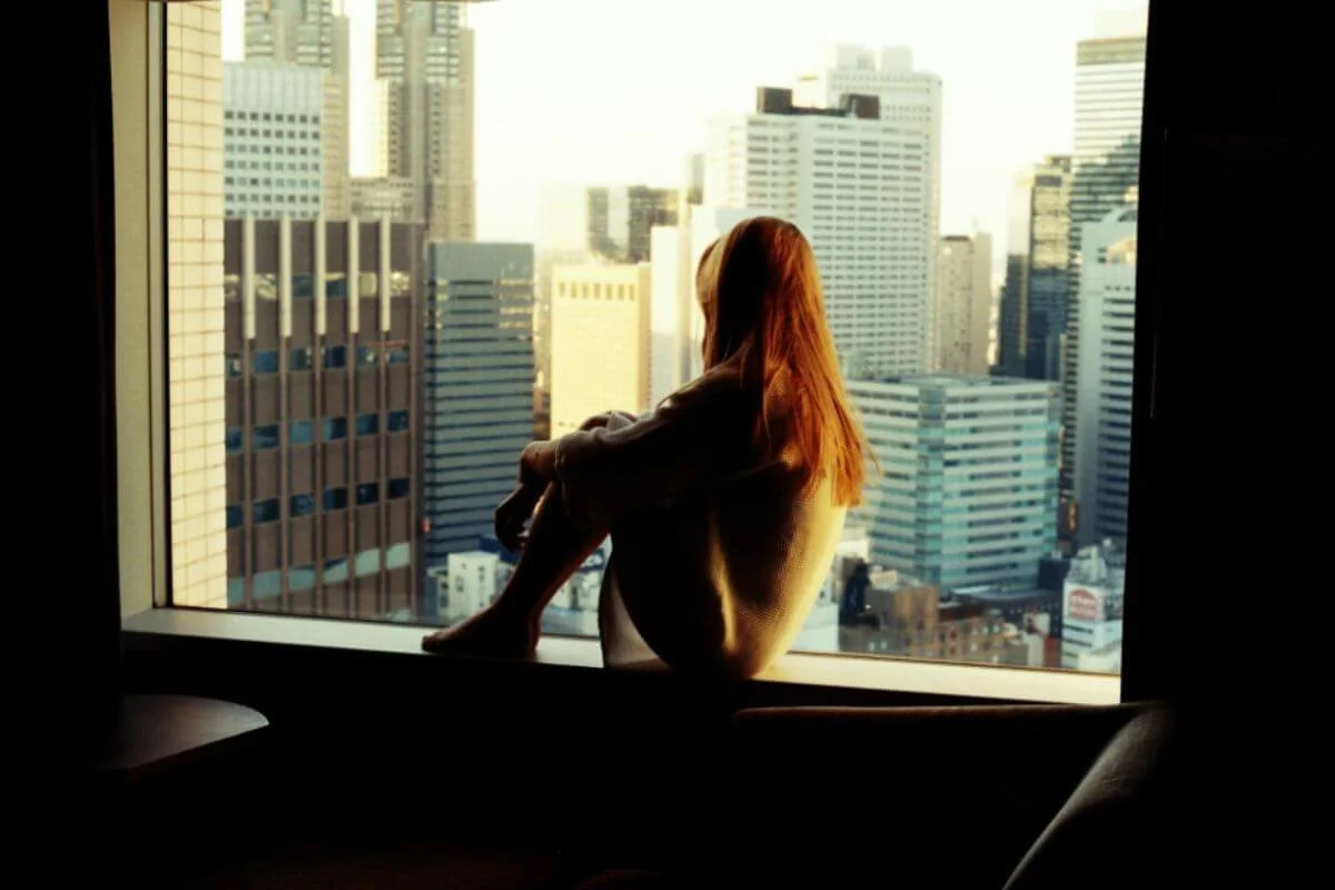 Woman staring outside the window looking at buildings