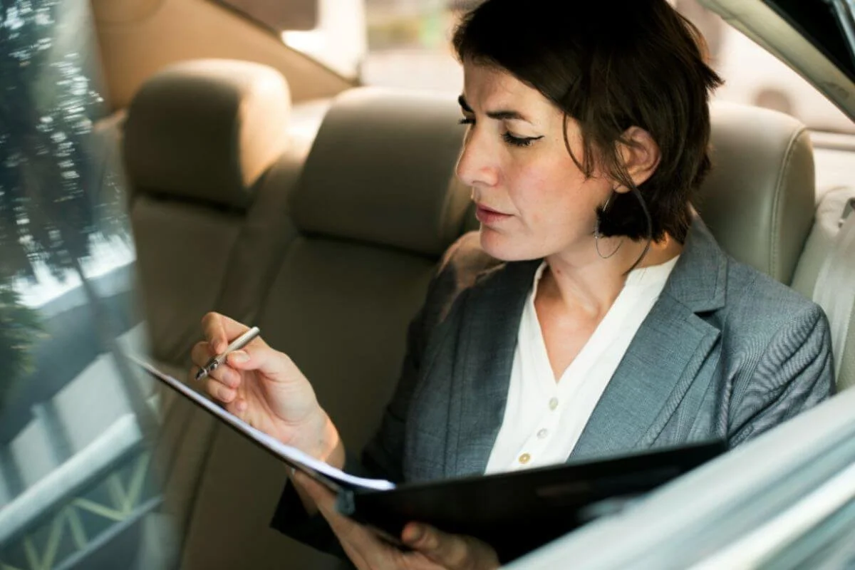 Woman in a car taking notes