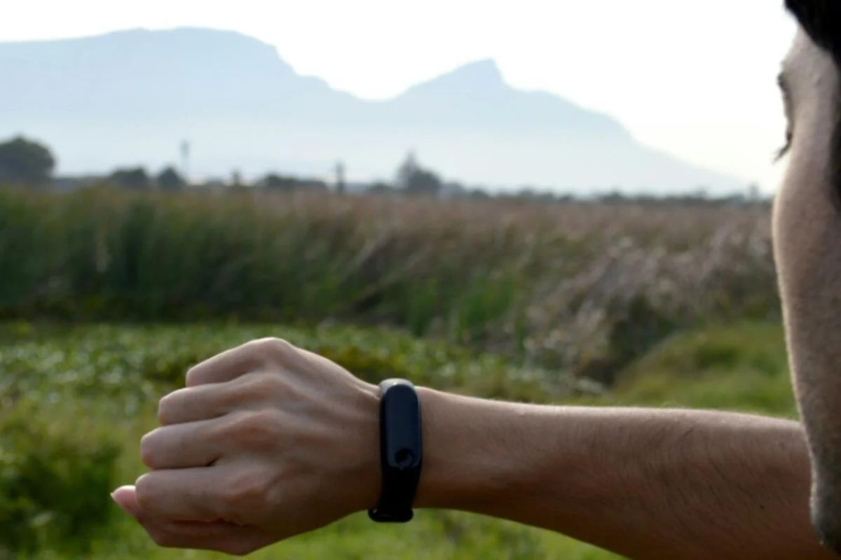 Woman checking a fitness tracker outdoors, one more data point sitting apart from the rest of her health history.
