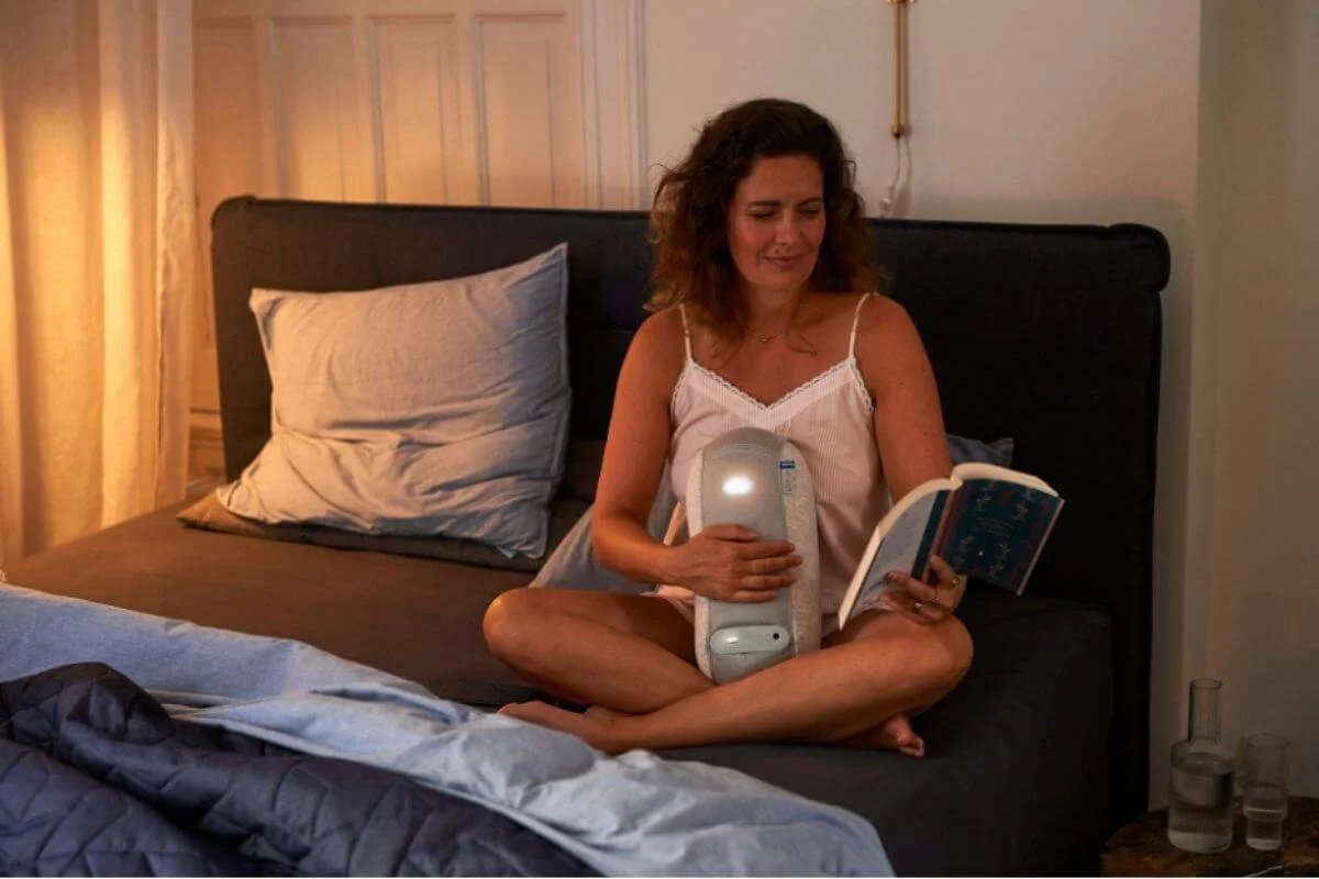 A woman sitting in her bed, reading a book
