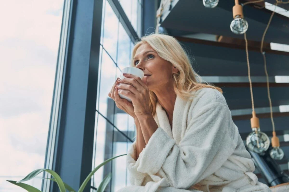 Woman drinking while staring outside the window