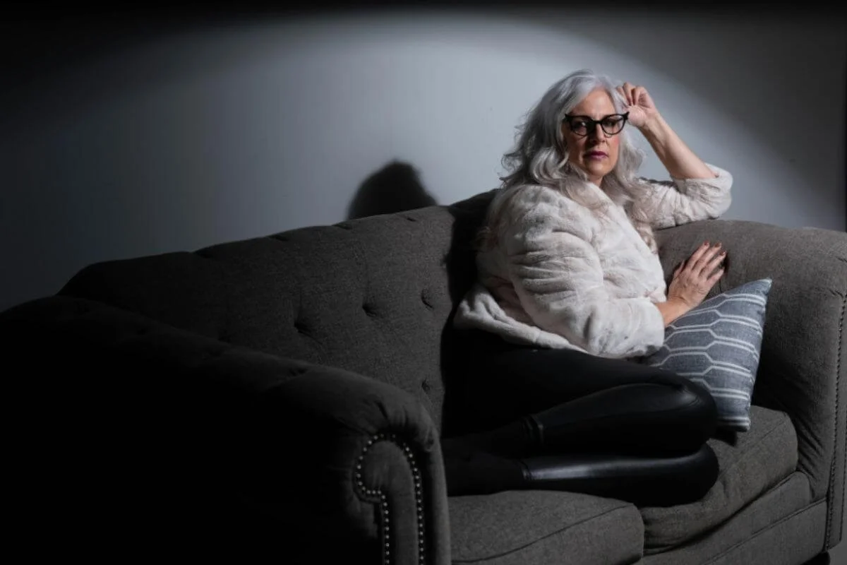 A woman in 60's sitting in a couch