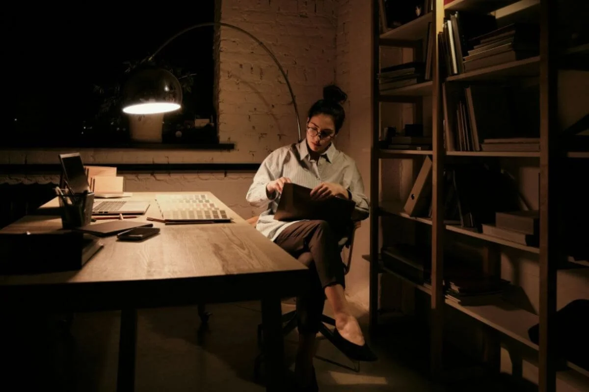 A woman working late at night in a dimly lit room