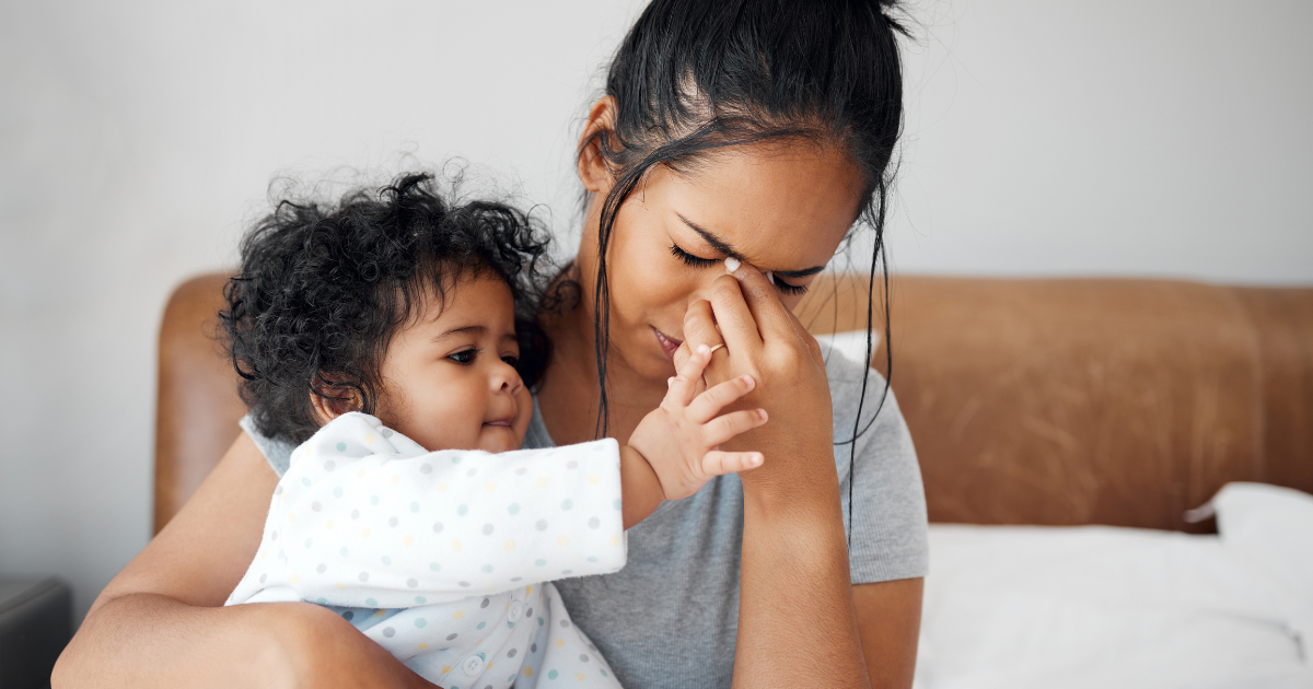 exhausted mom holding toddler on bed