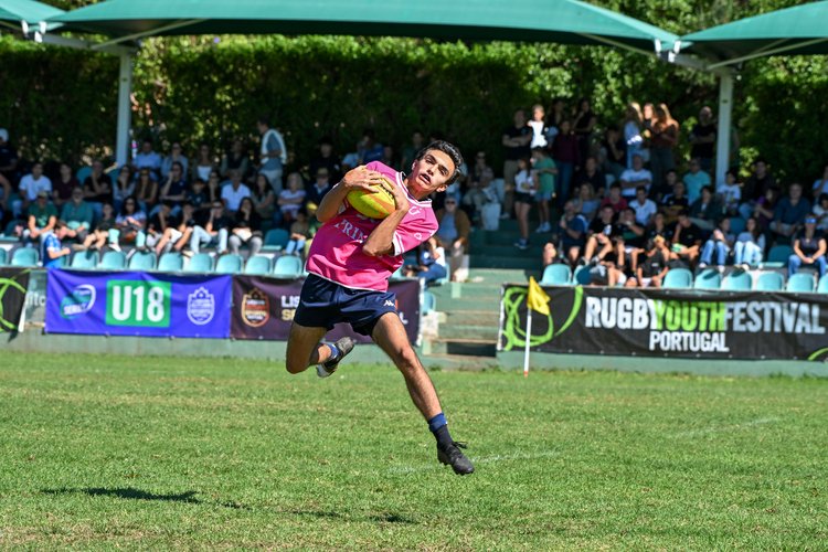 U18 player in action during a match at the Portugal Rugby Youth Festival in Lisbon, carrying the ball at speed in front of the main stand.