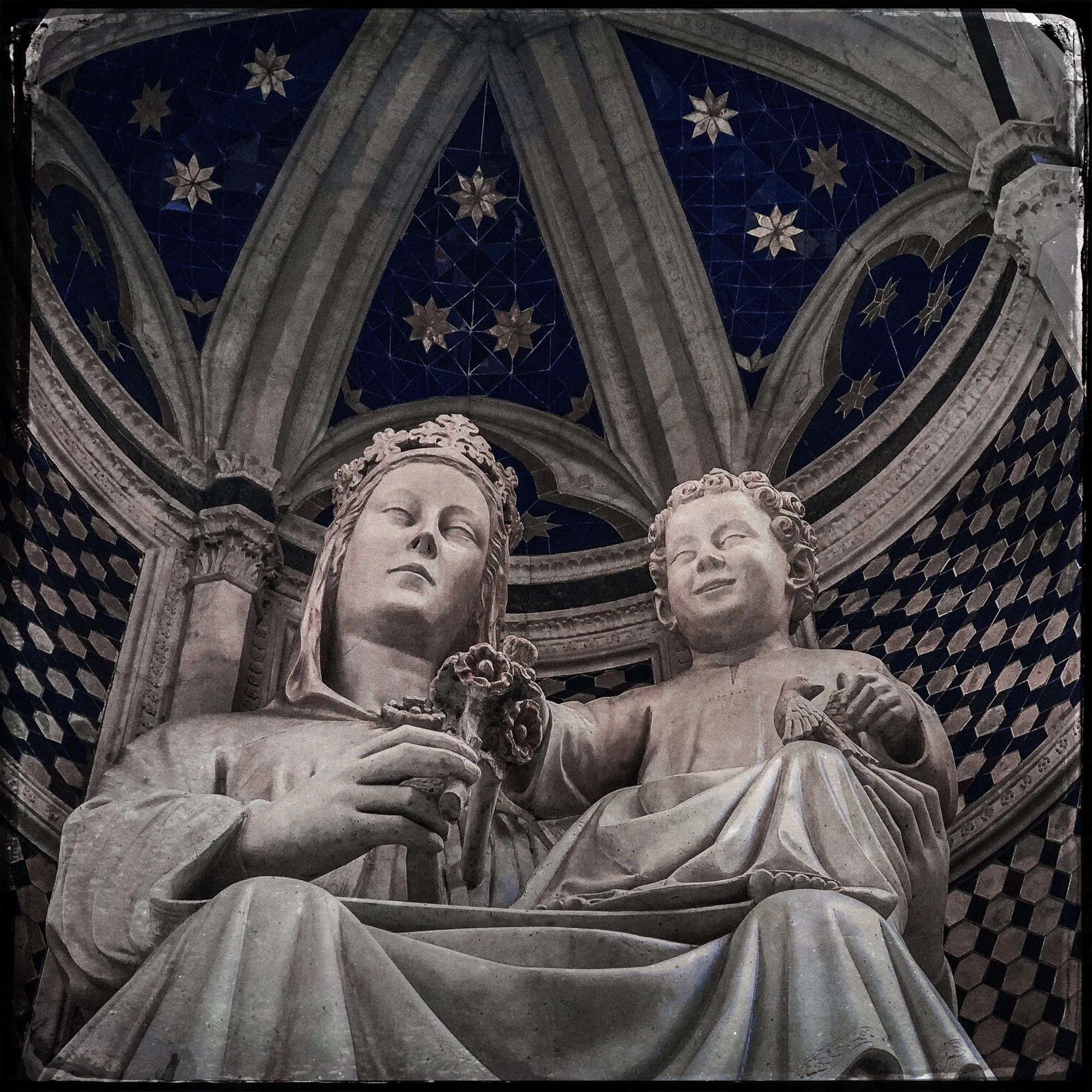 Statue of the Virgin Mary and baby Jesus inside a church with a starry night sky painted on the ceiling.