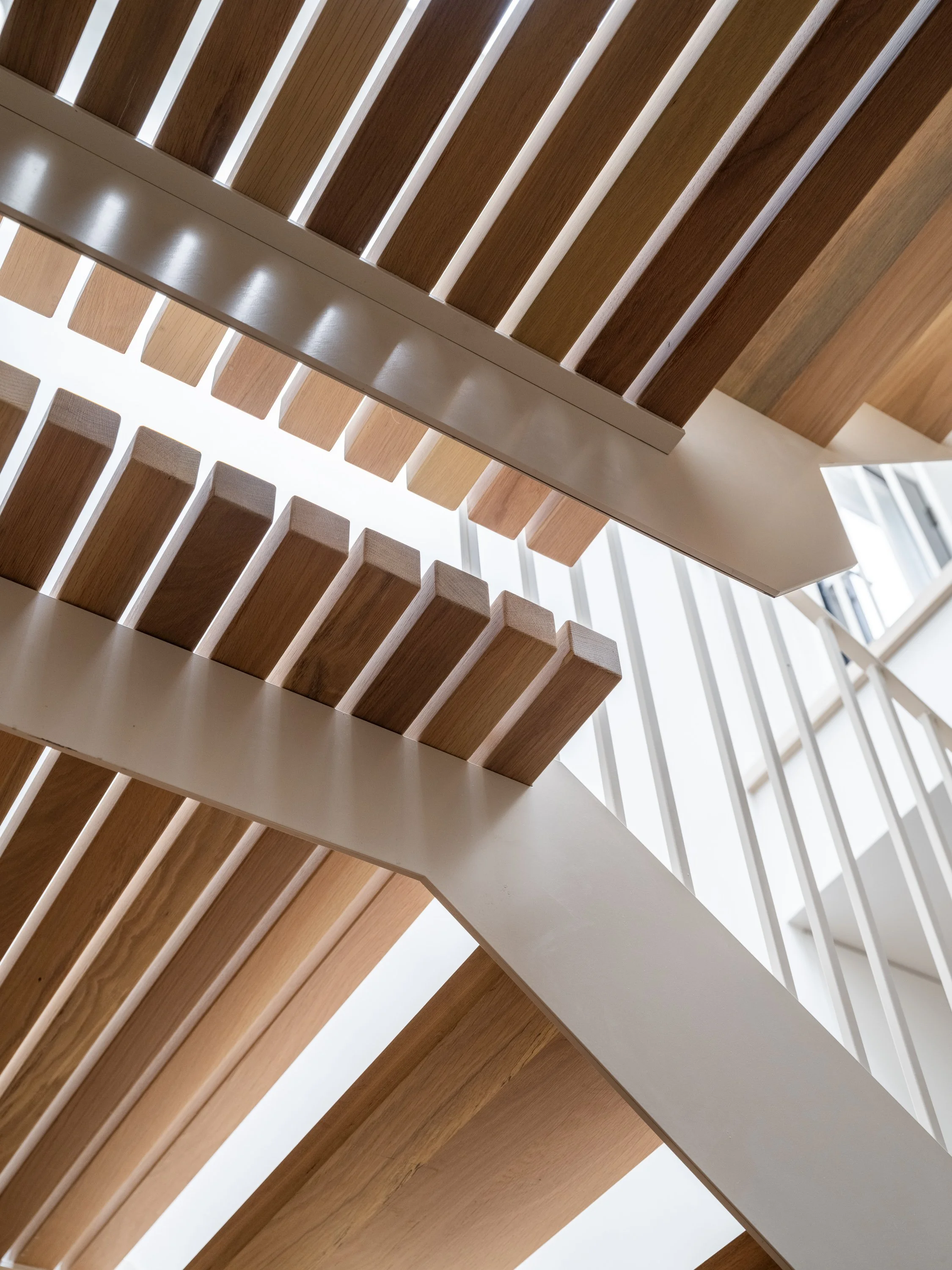 Enchaînement  des paliers en caillebotis de chêne blanc de l’escalier sur mesure Trafalgar, un projet pensé pour relier harmonieusement plusieurs niveaux.
