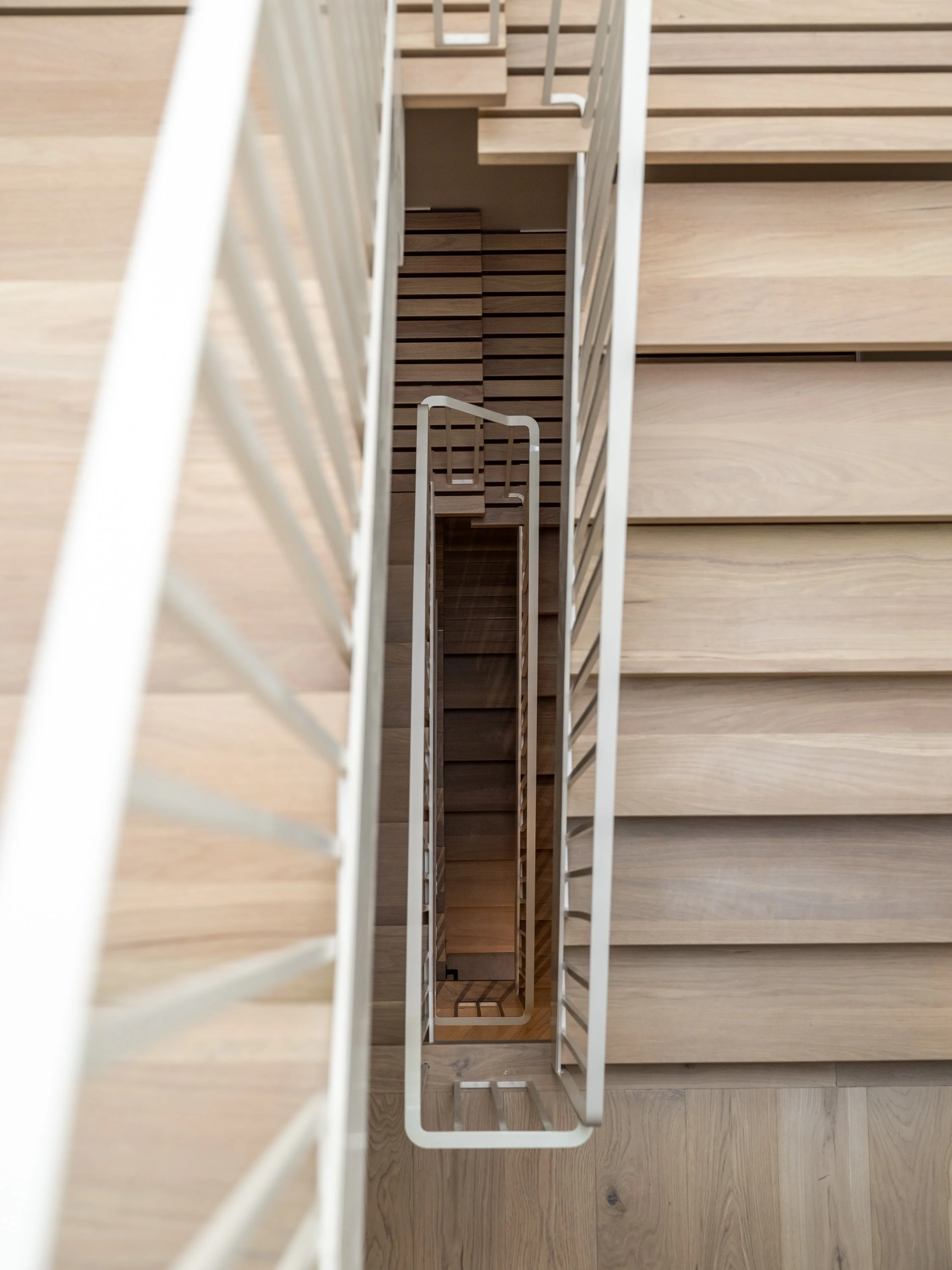 Vue plongeante des différentes volées de l’escalier architectural du projet Signature Trafalgar, soulignant la continuité du garde-corps et la fluidité de sa conception.