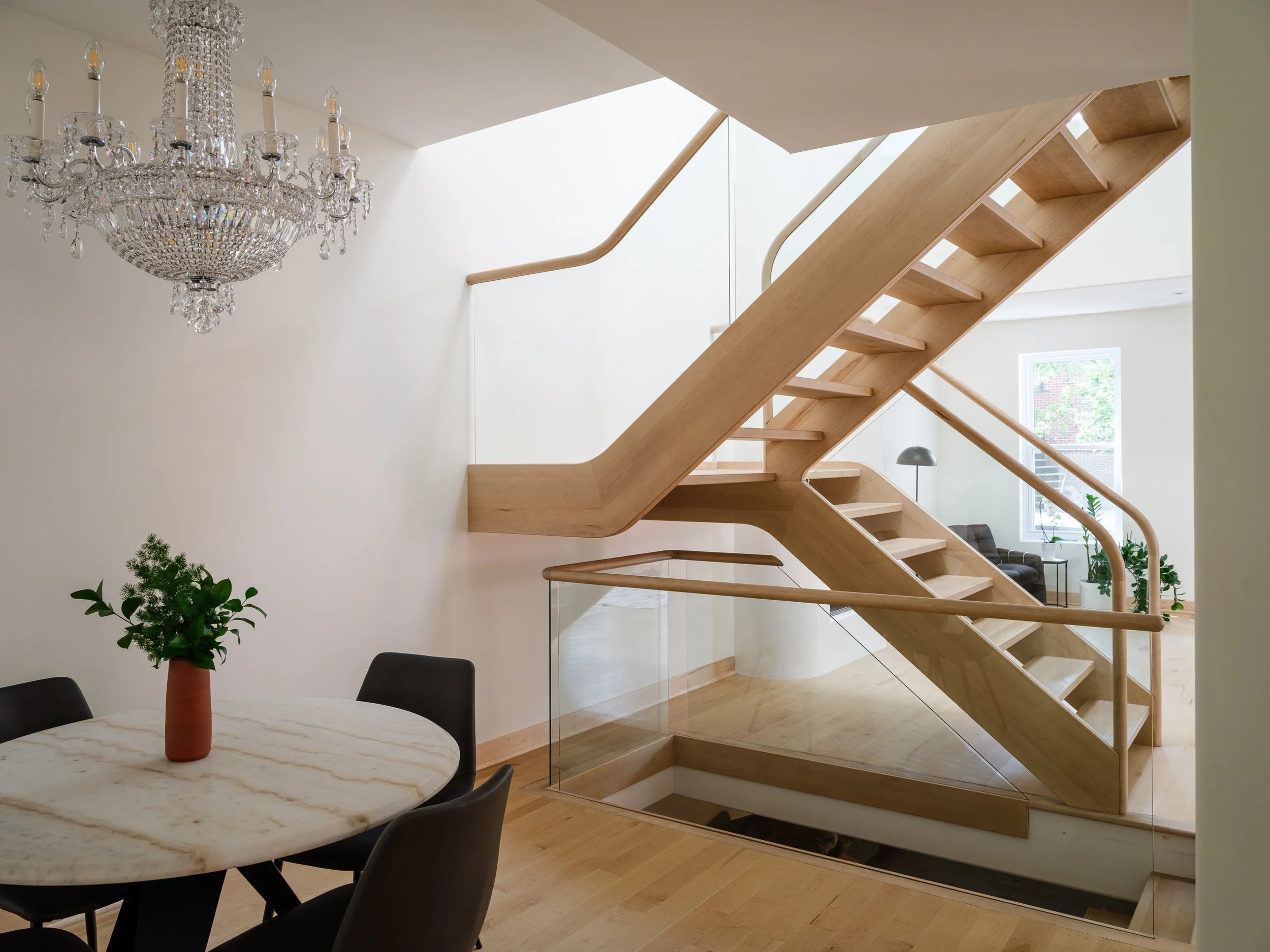 Escalier courbe en érable massif reliant plusieurs niveaux d’une résidence contemporaine à Montréal.
