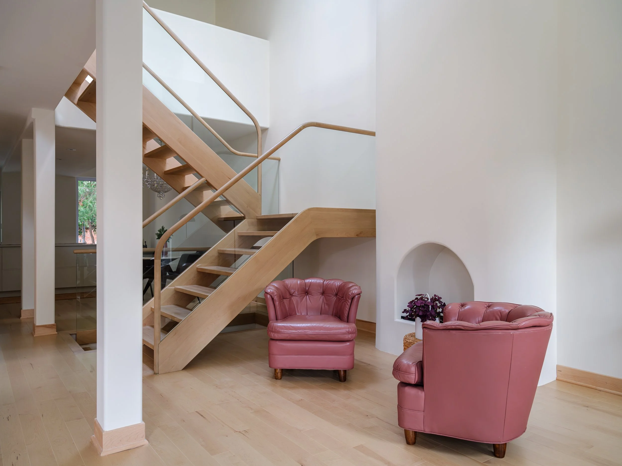 Escalier sculptural en bois et verre conçu pour préserver la lumière naturelle de la résidence.