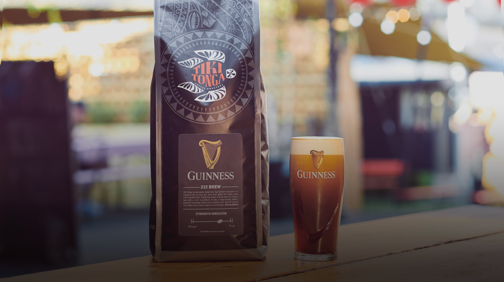 A packet of Guinness coffee beans is next to a pint of freshly poured Guinness.  