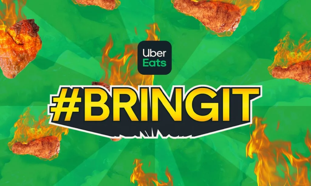 An Uber Eats app icon above the hashtag #BringIt on a green and orange flame background.  