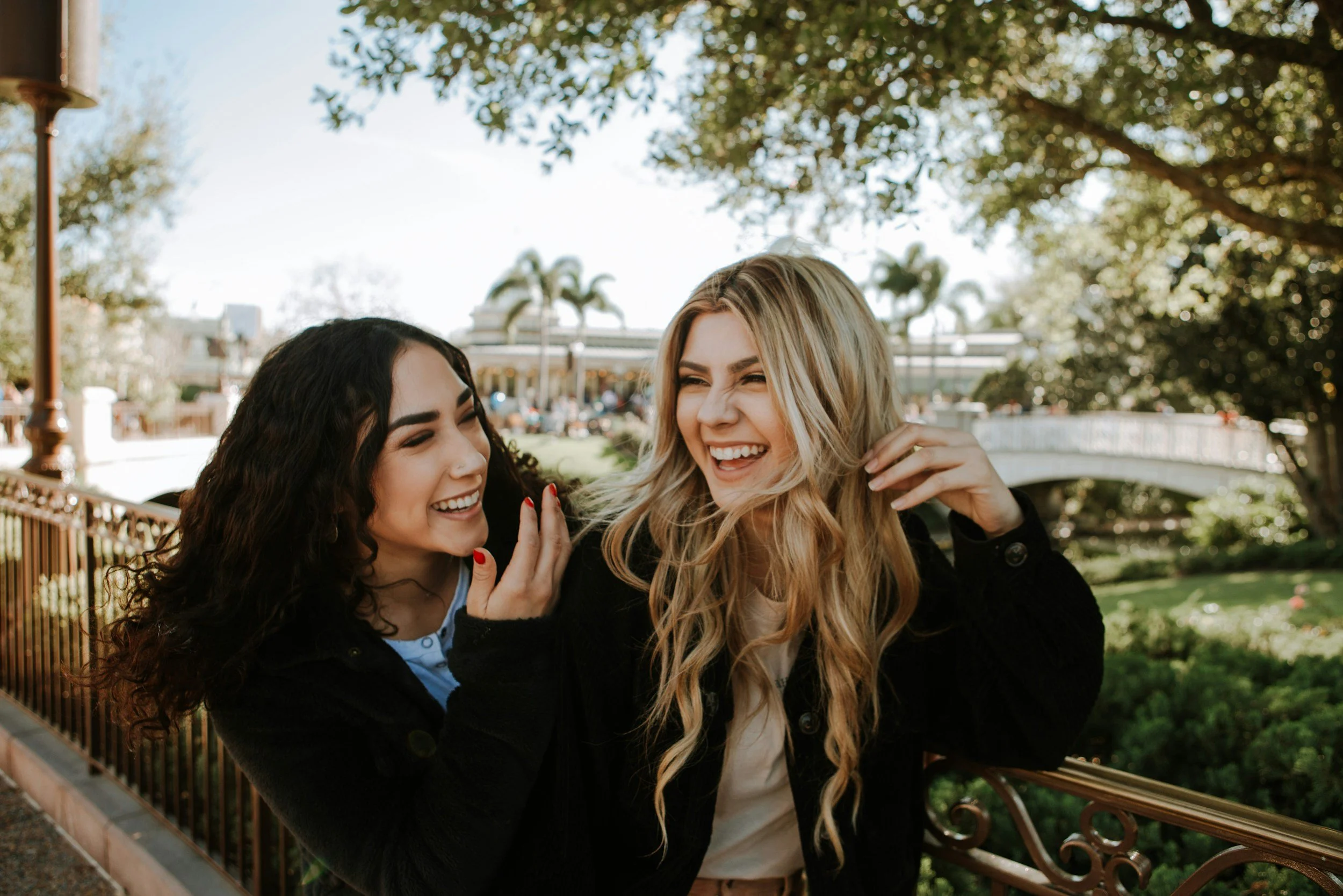 Two laughing young women talking outdoors in a park.