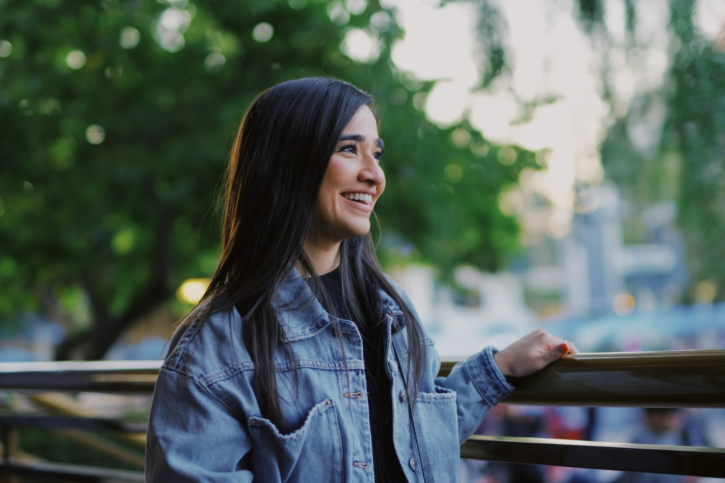 happy woman with black hair and jean jacket