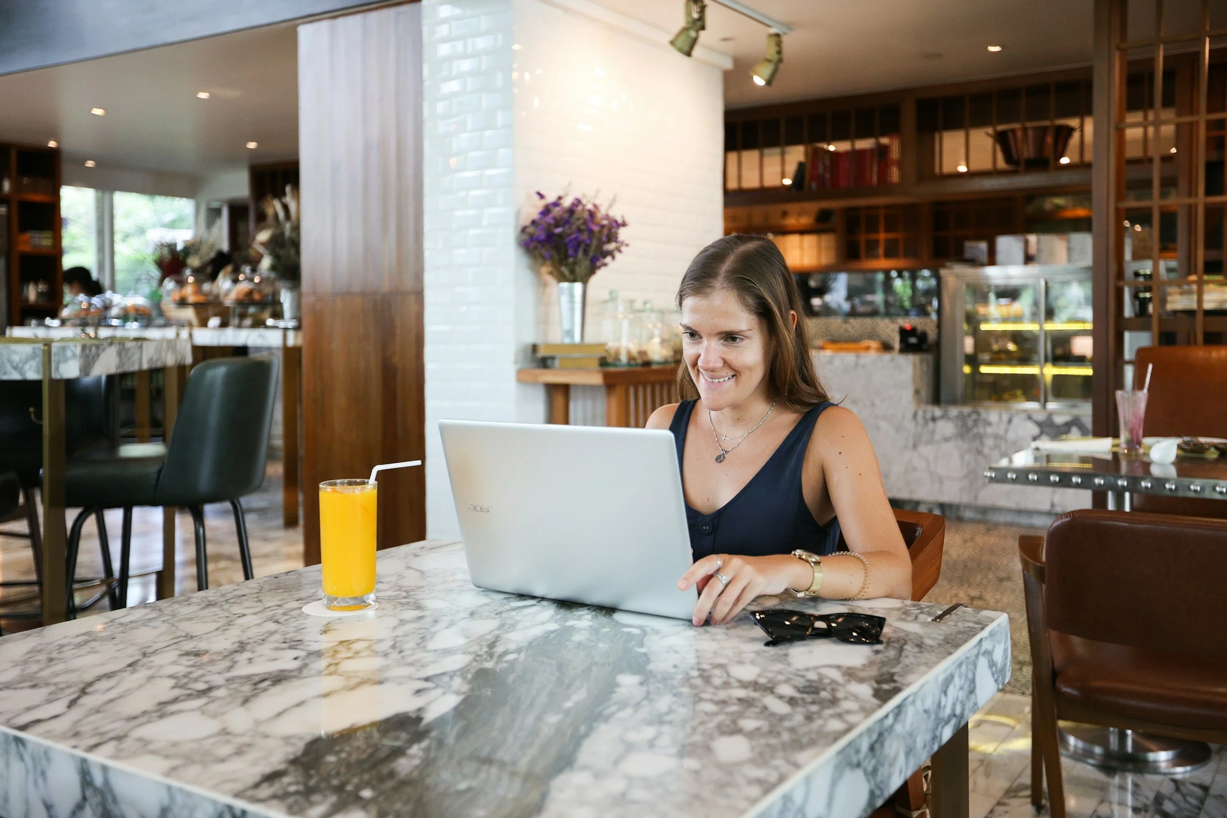 woman with brown hair on laptop at a restaurant.
