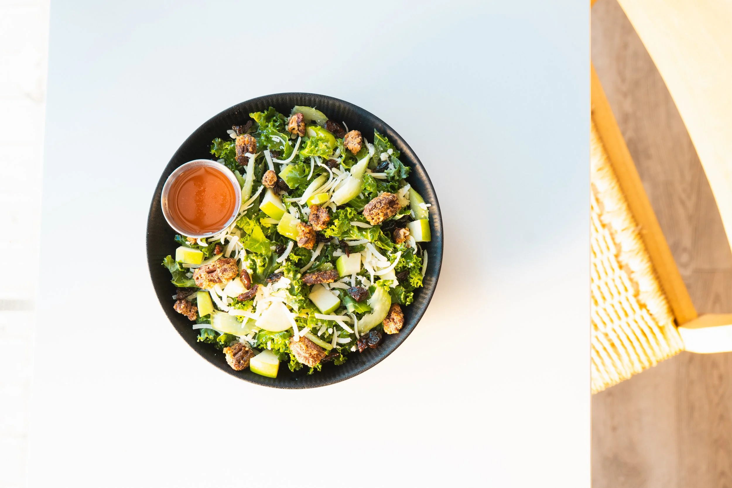 bowl filled with leafy greens, croutons, shredded cheese, and side of salad dressing