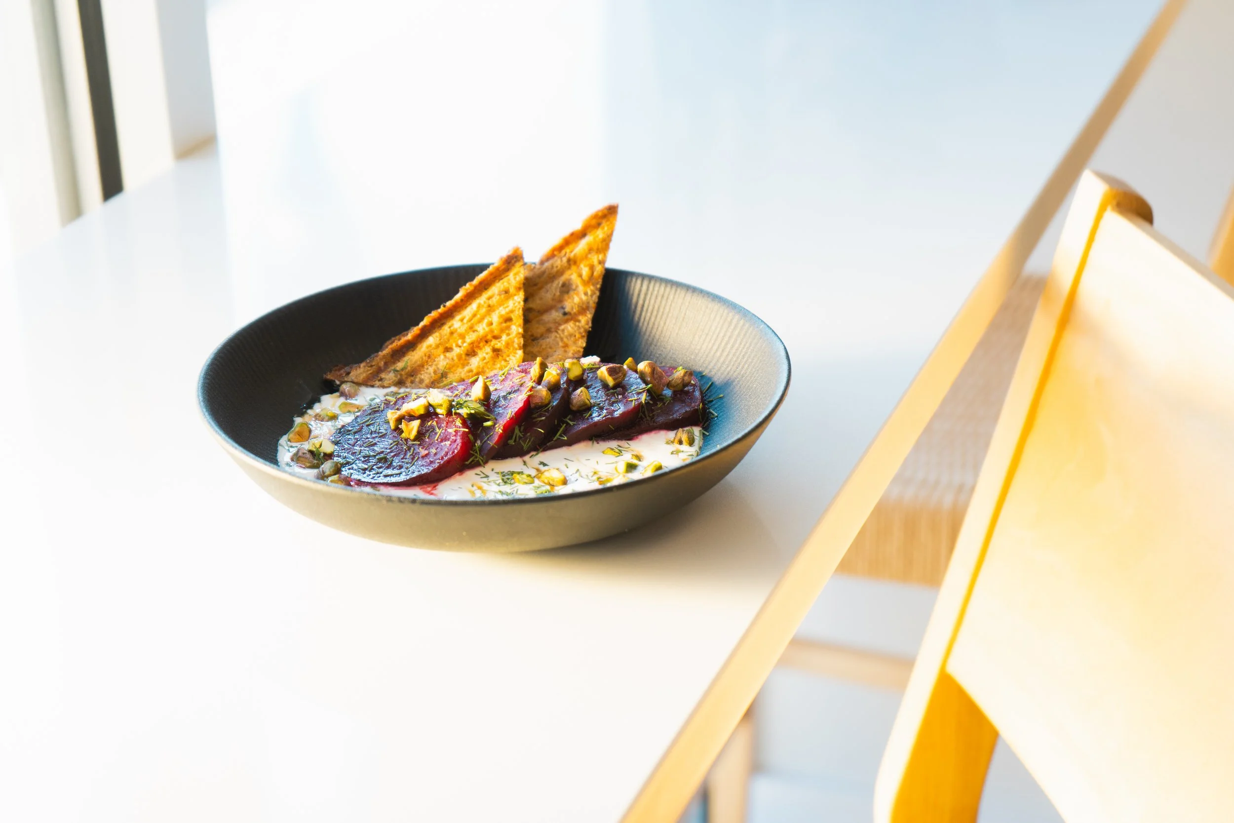 yummy looking grain bowl topped with beets, herbs, and little toast triangles.