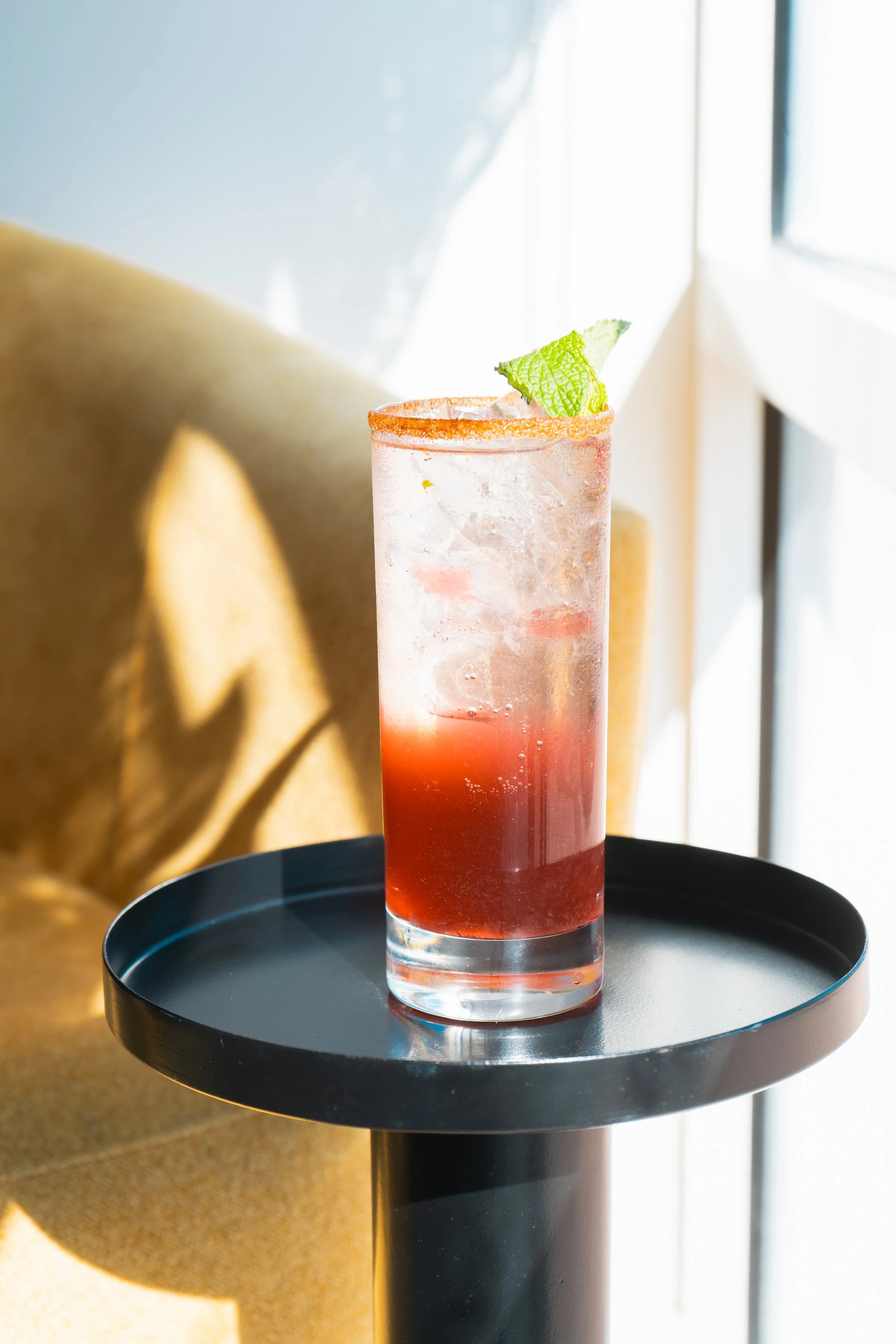an iced, refreshing-looking pink cocktail with lime garnish