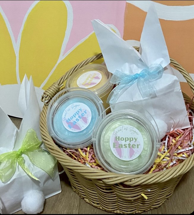 Easter basket with "Hoppy Easter" labeled containers, paper bags with ribbon bows, and colorful shredded paper.