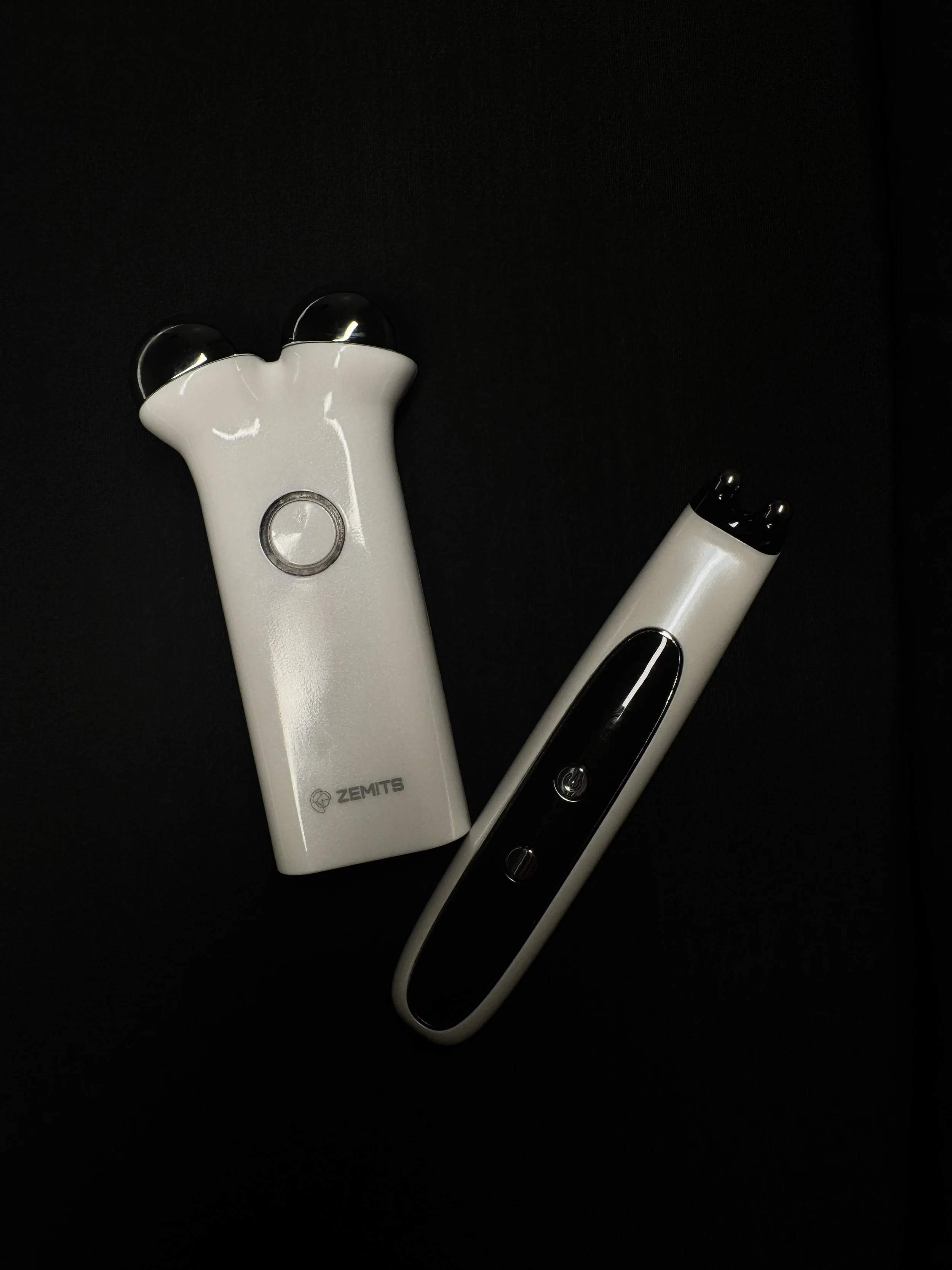 Electrical massager device with two rounded massage heads and a control unit on a black background.